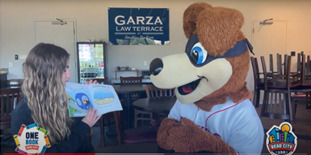 Woman with blond wavy hair reading to the Tennessee Smokies mascot