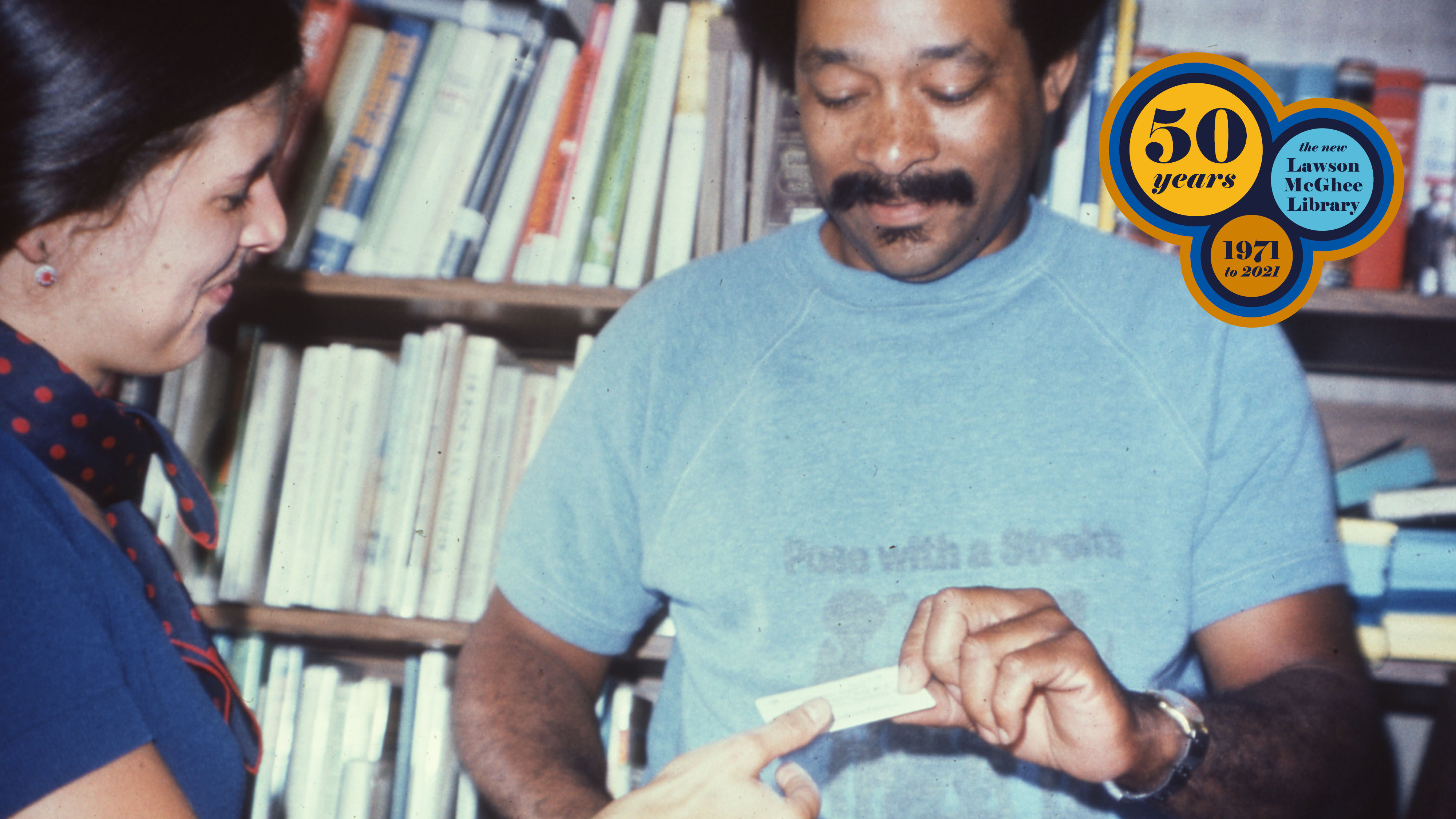 Photo of man being handed a library card. 