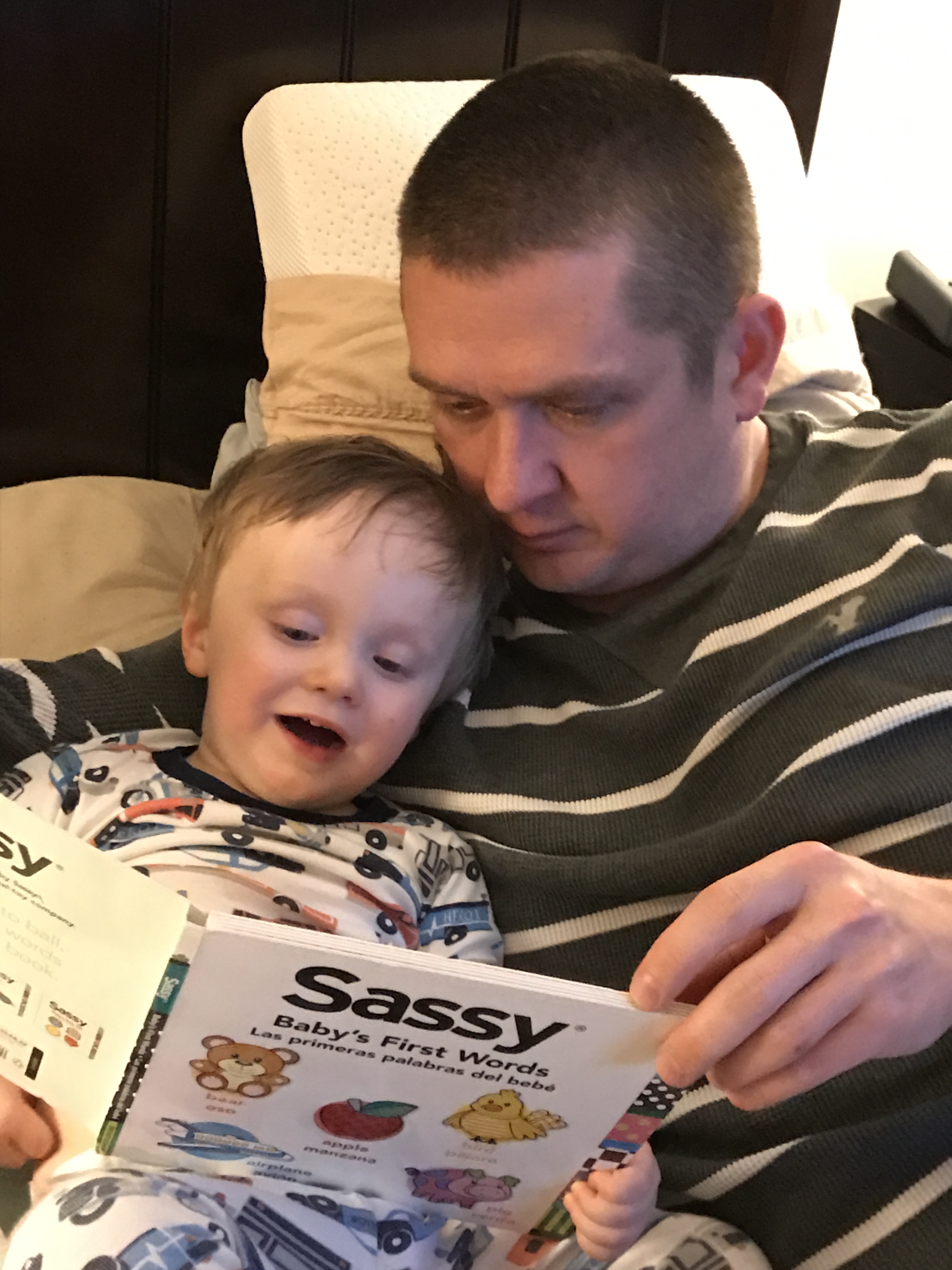 Chase (22months) reading in bed with man. 