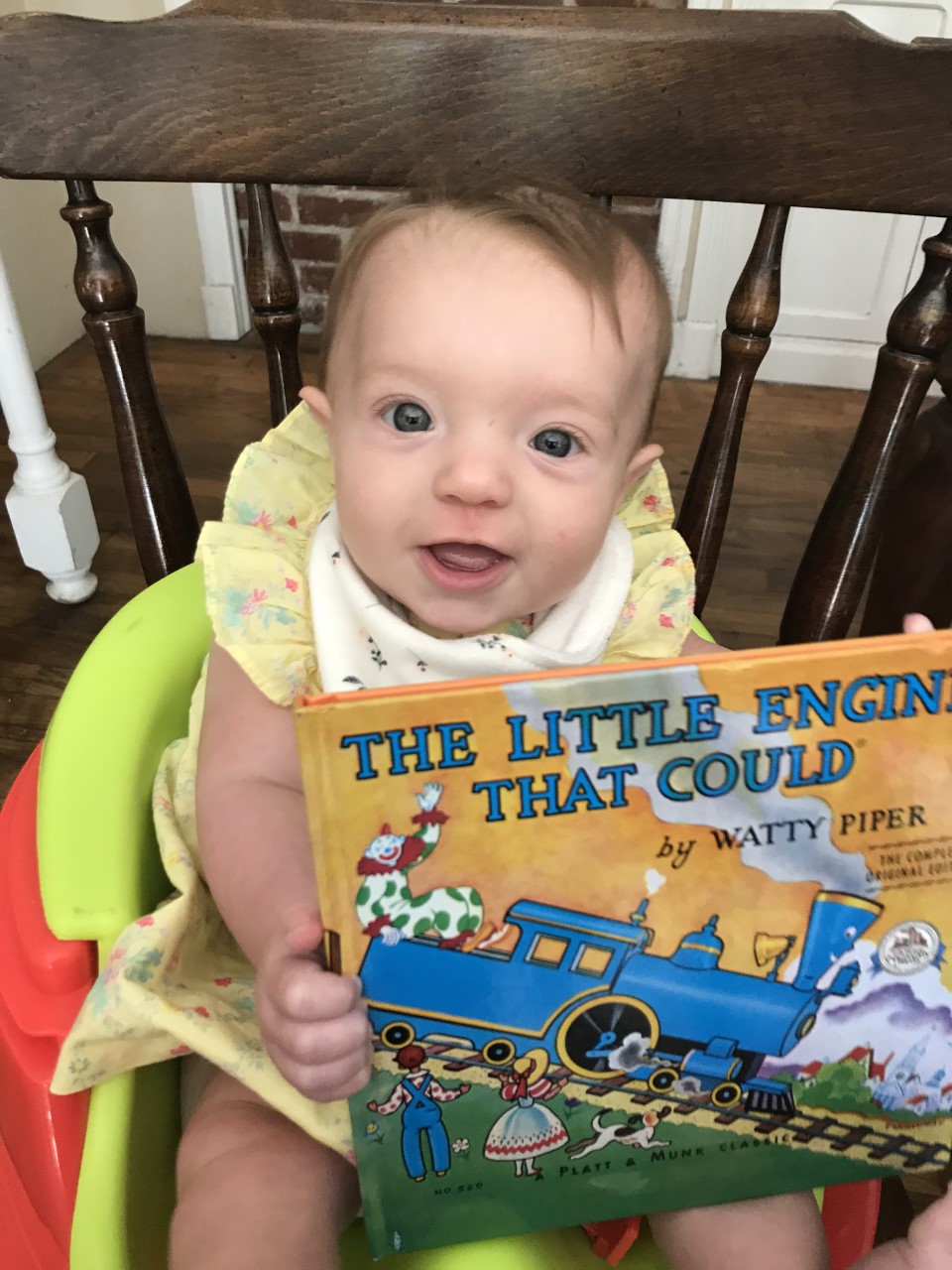 Baby holding The Little Engine that Could. 