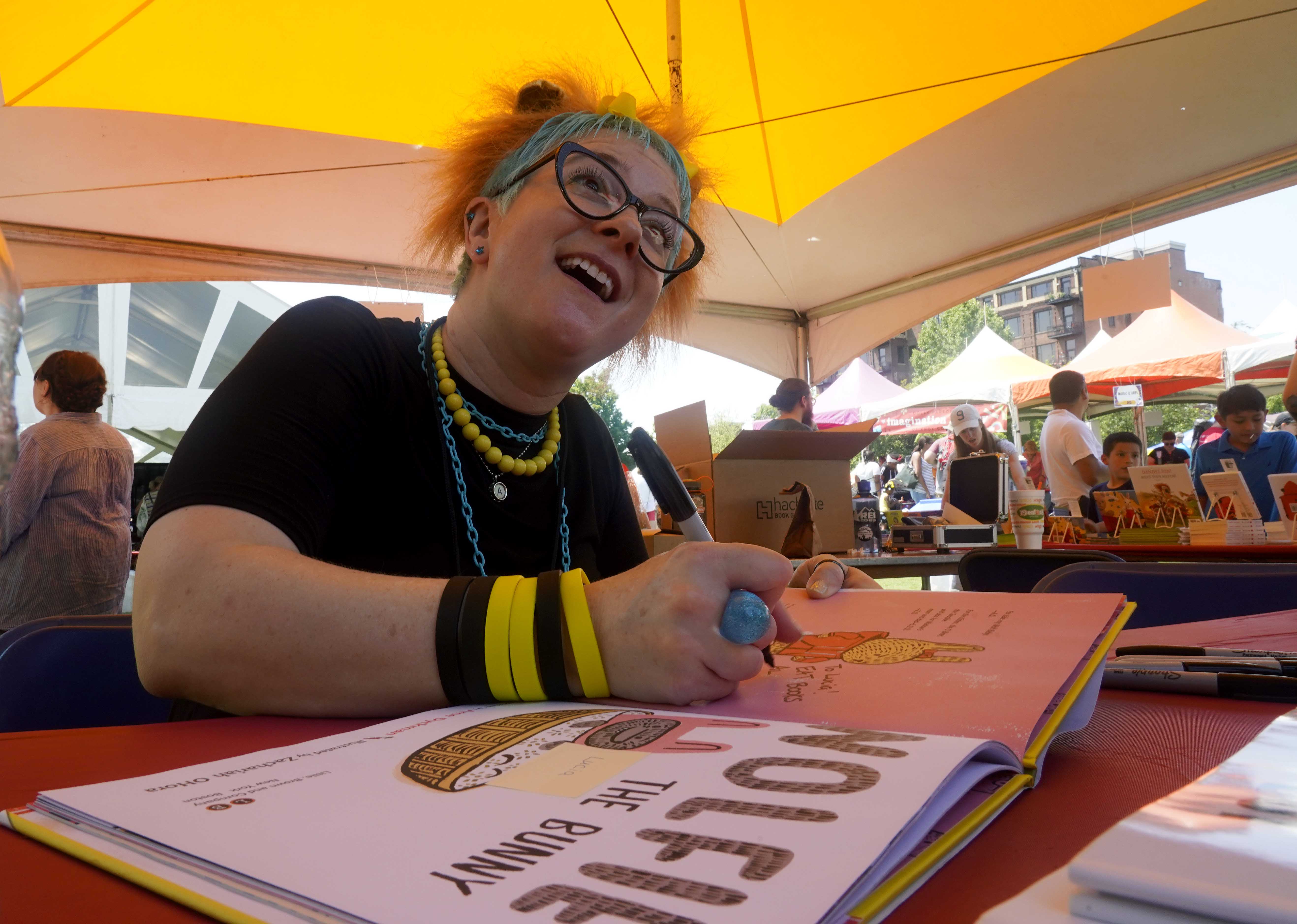 Author signing her book and smiling at guests during the Children’s Festival of Reading