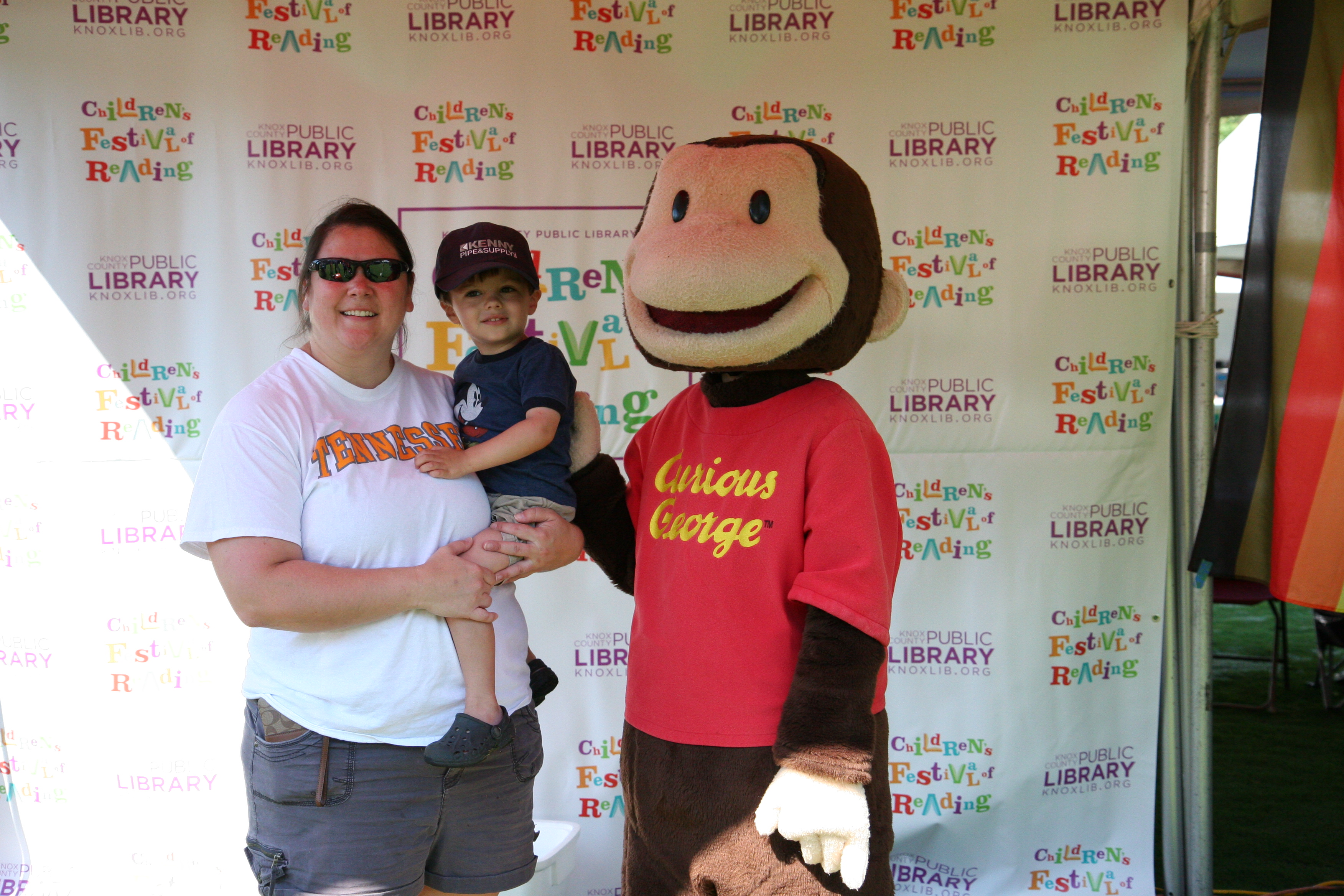 Mom and son posing with man in Curious George suit