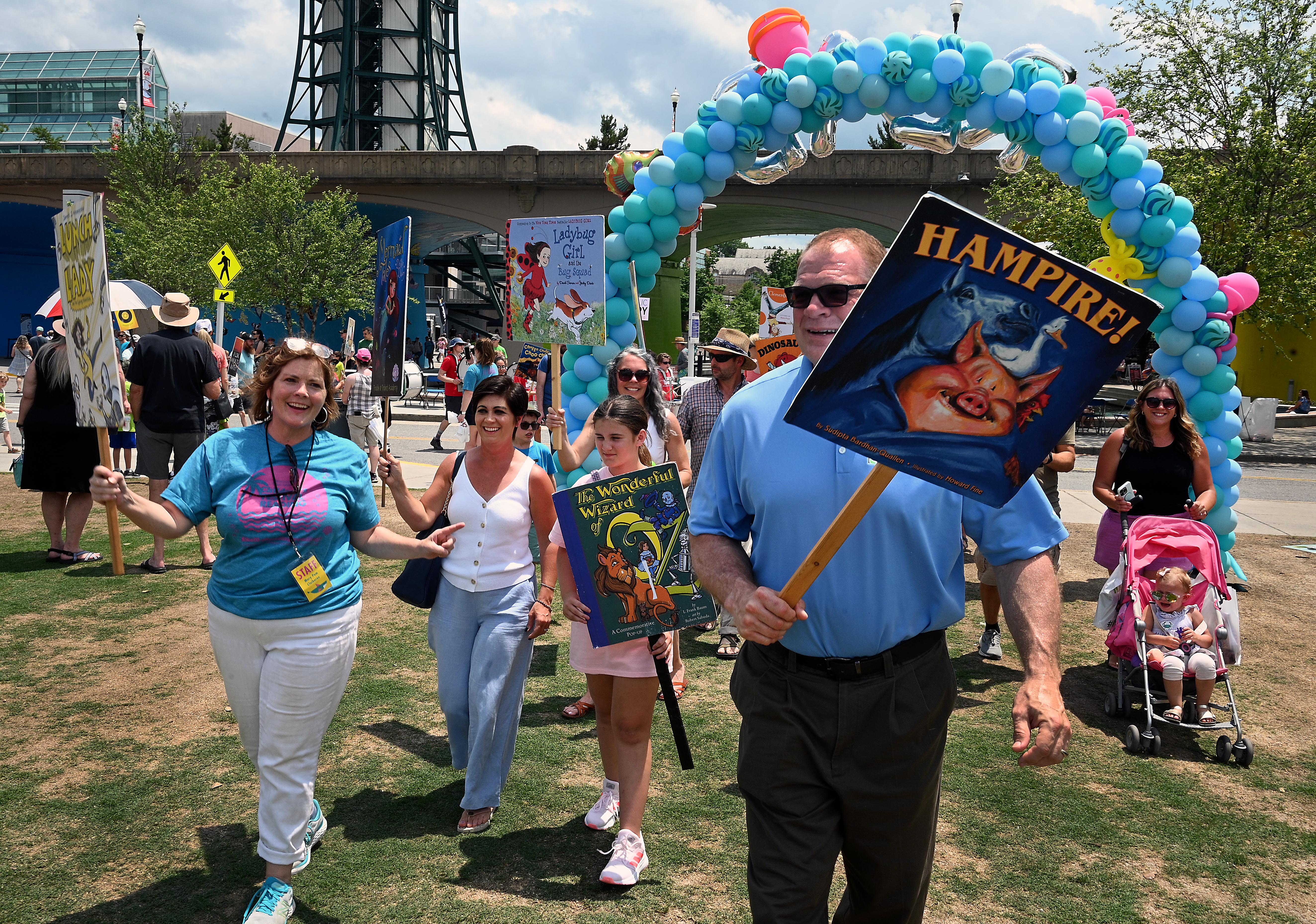 People walking in a parade with large book signs