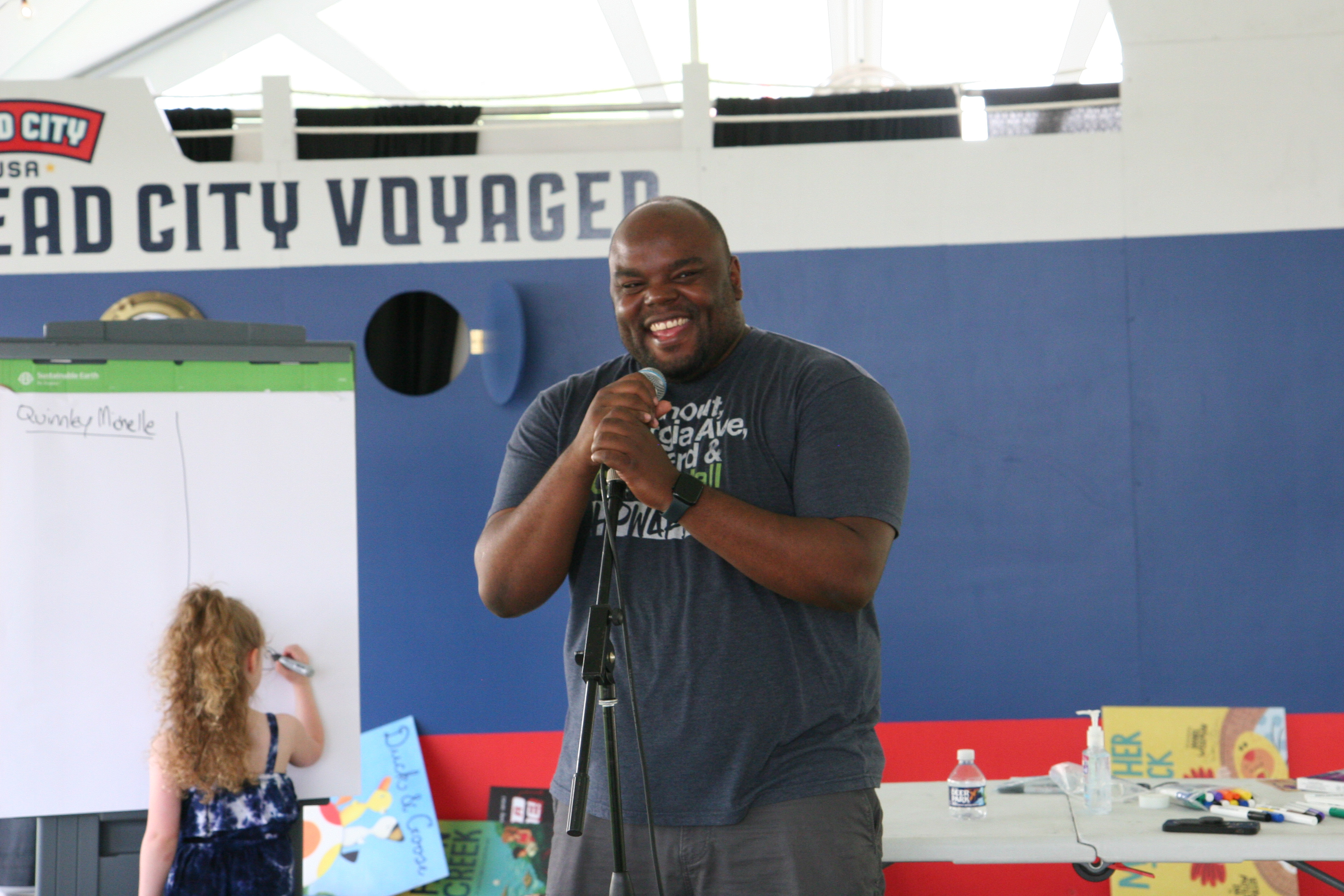 Photo of author Kwame Mbalia in front of painted Read City Voyager ship background