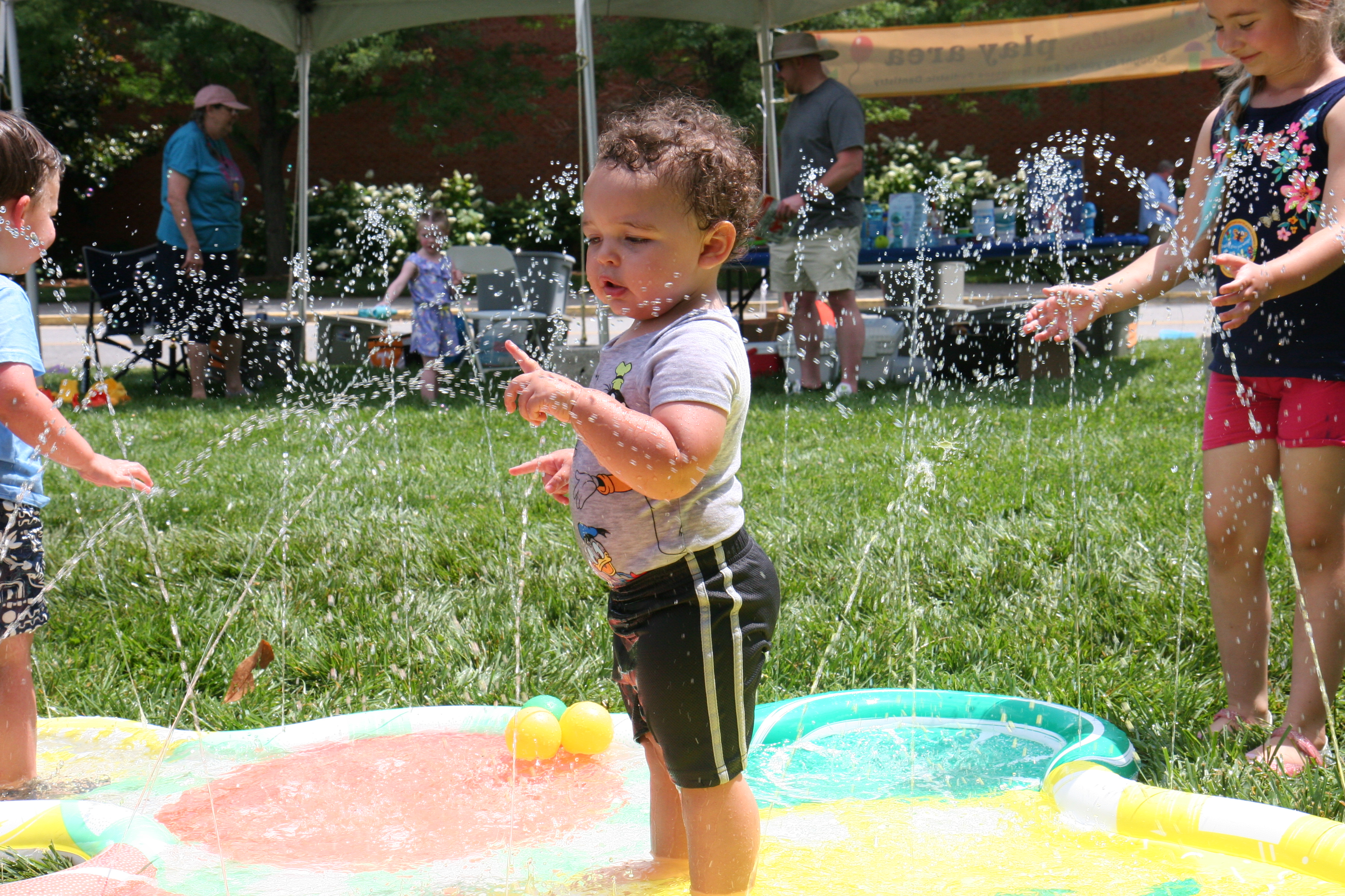 Photo of toddler boy standing in a small fountain water toy