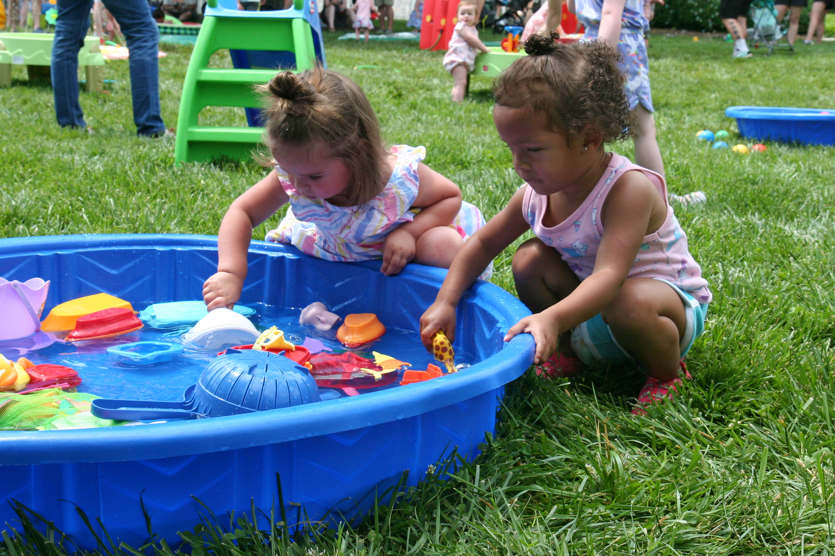 Photo of two toddlers leaning over a baby pool filled with toys