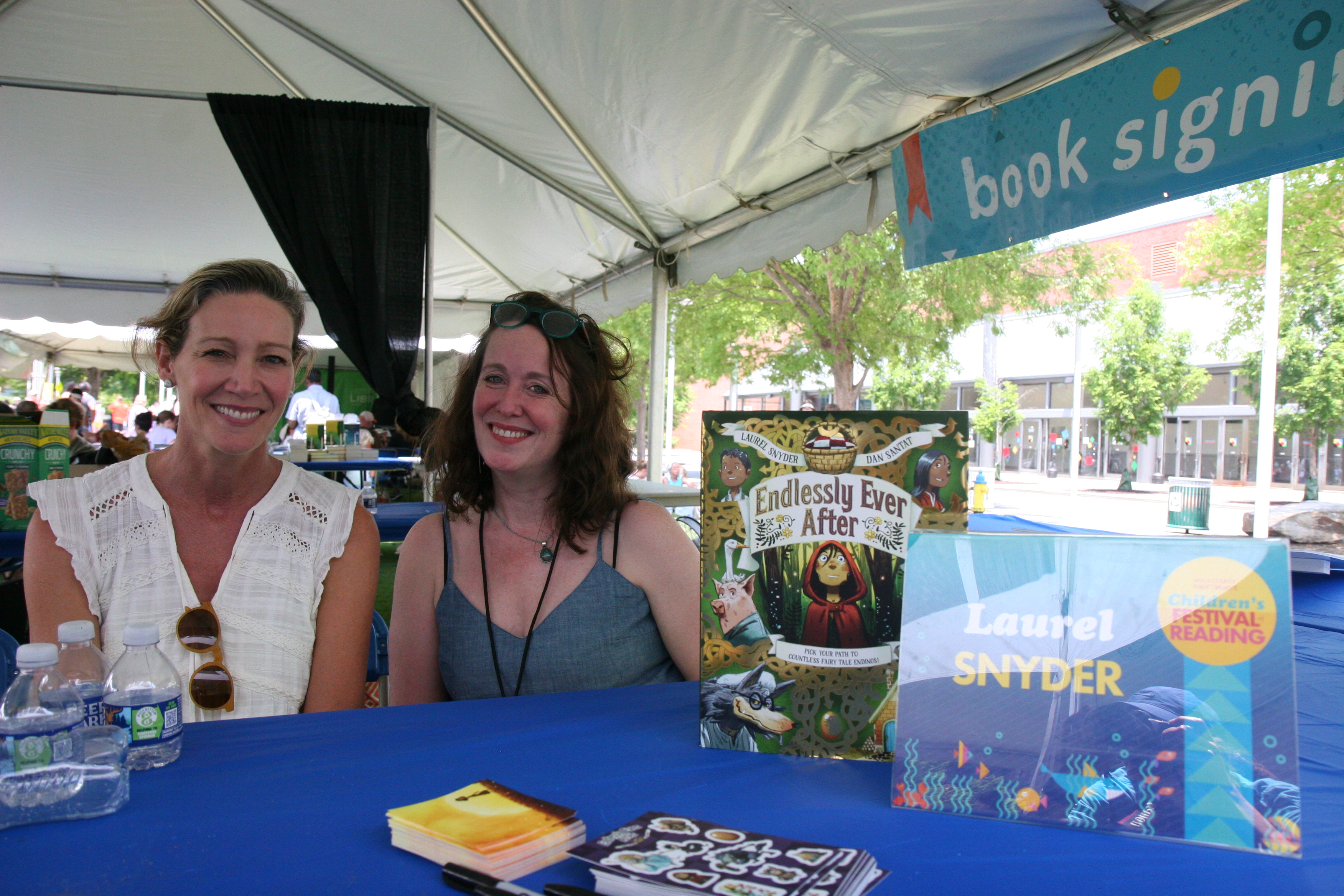 Laurel Snyder and festival volunteer pose with the cover of Snyder's latest book