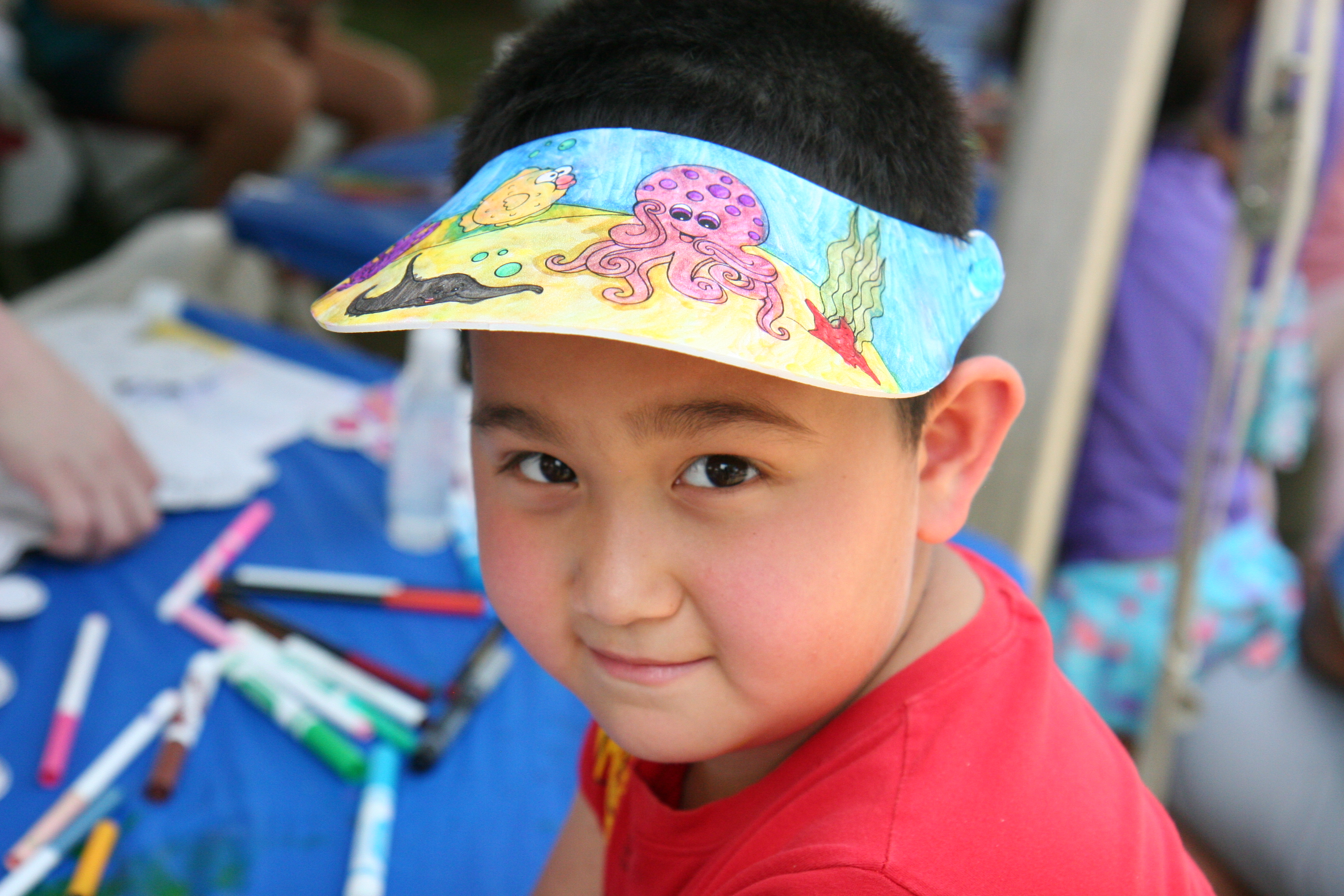 Photo of young man wearing a foam visor he colored