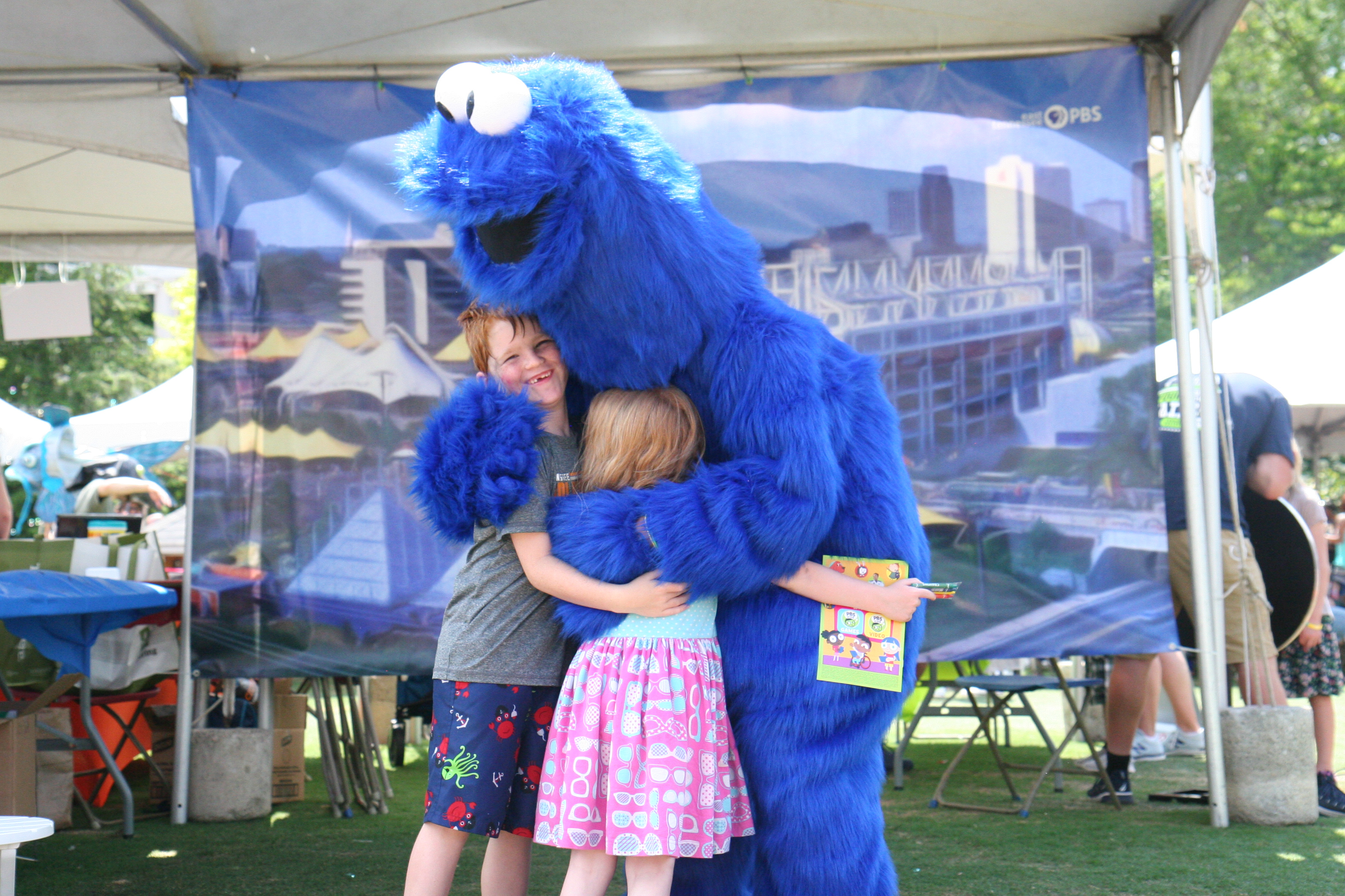 photo of two small children hugging a Cookie Monster costumed character