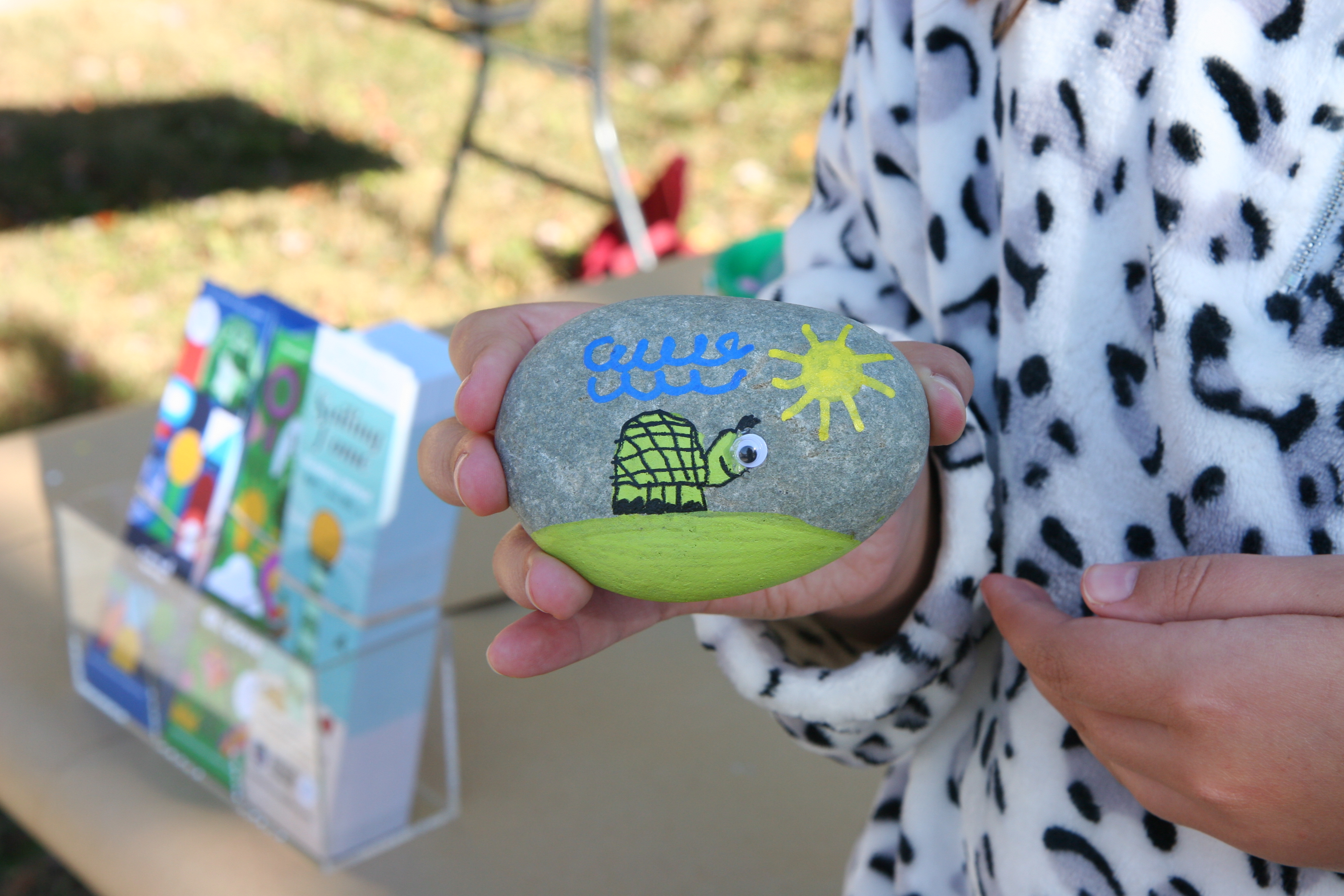 girl holds up a rock painted with a turtle