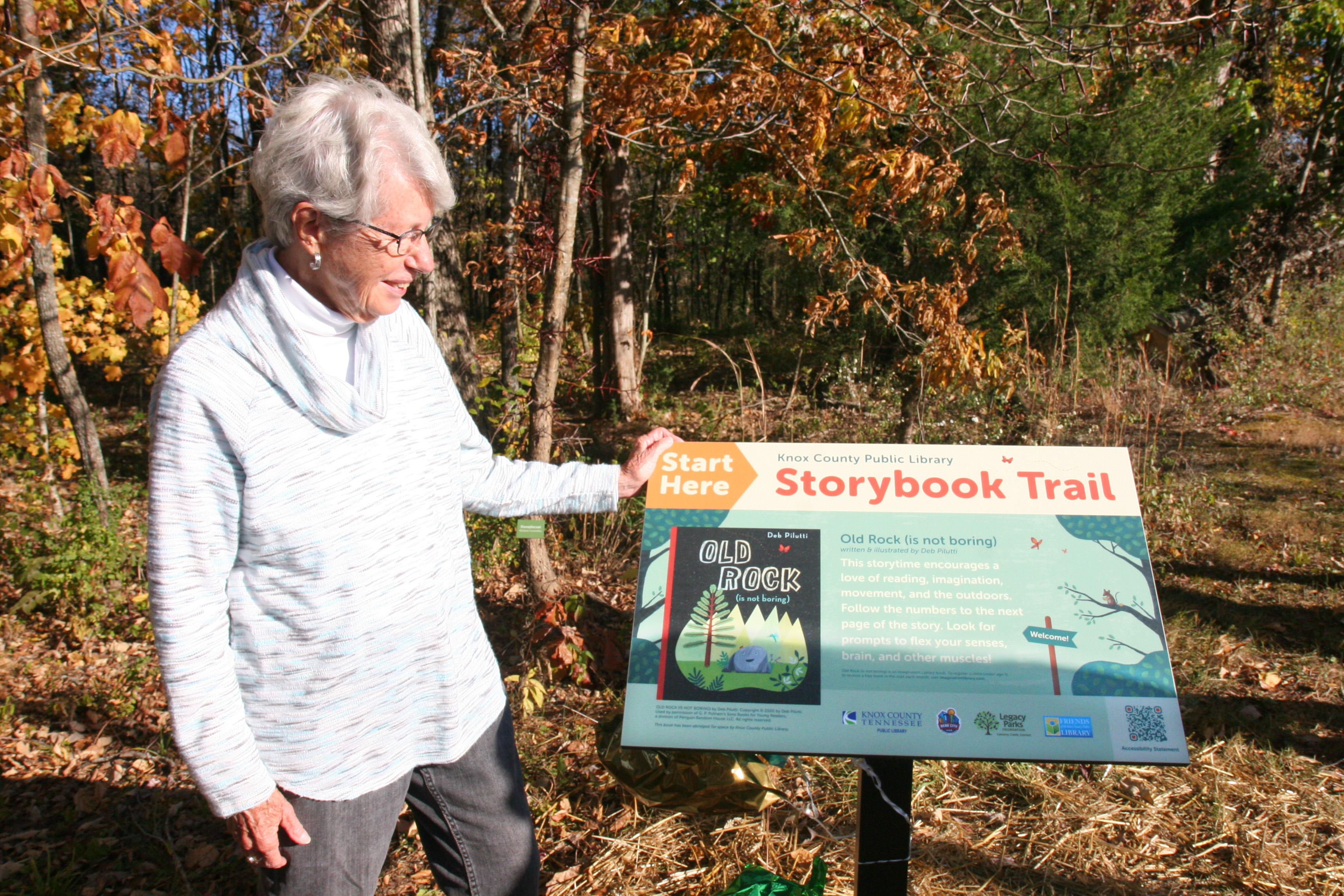 Louise Collier stands next to a Storybook Trail panel