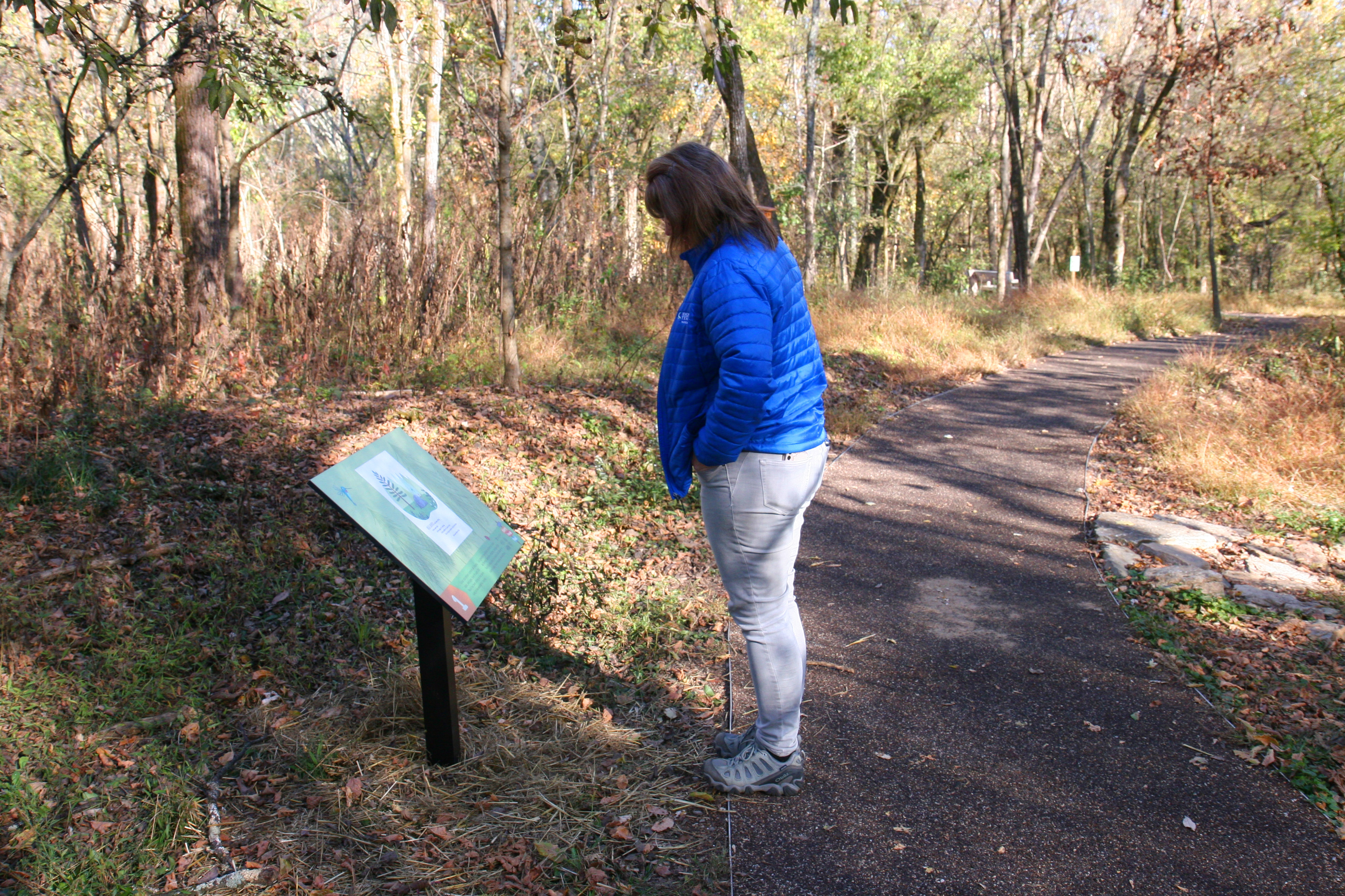 woman in blue jacket stands over story trail panel