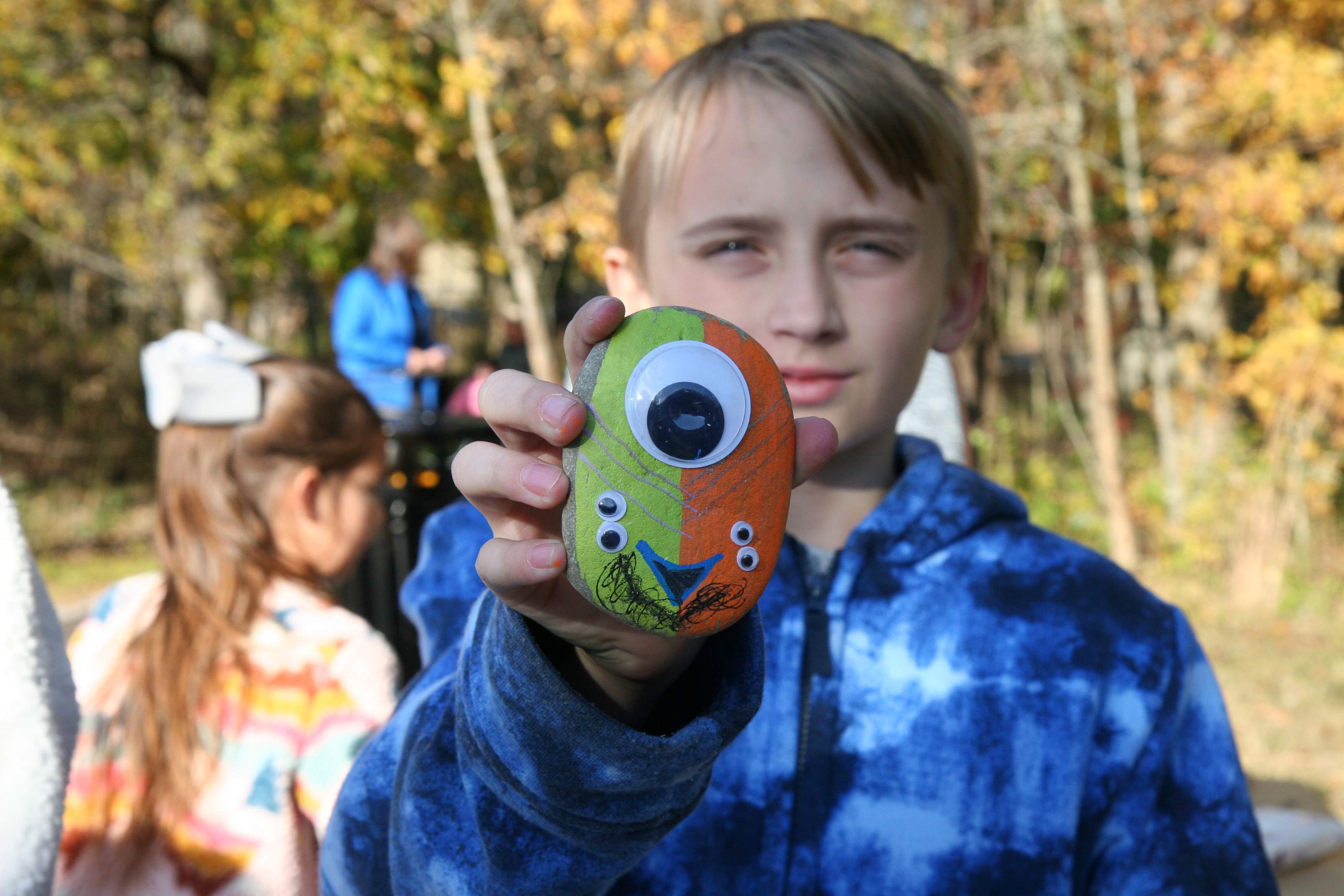 an older boy shows off his monster-painted green and orange rock