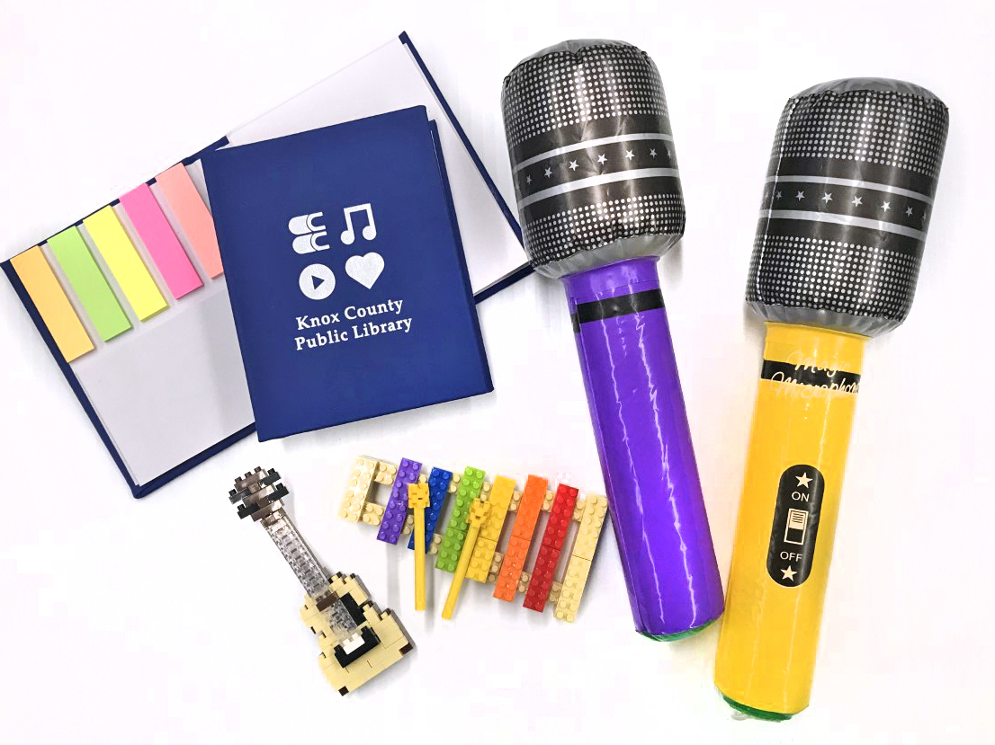 photo of notepad with Knox County Public Library on the cover, building block instruments (guitar and xylophone) and inflatable microphones in purple and yellow