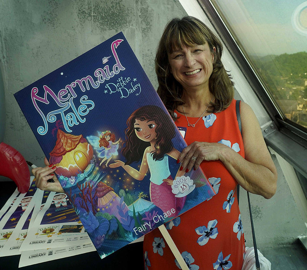 Debbie Dadey holds enlarged book cover of Mermaid Tales