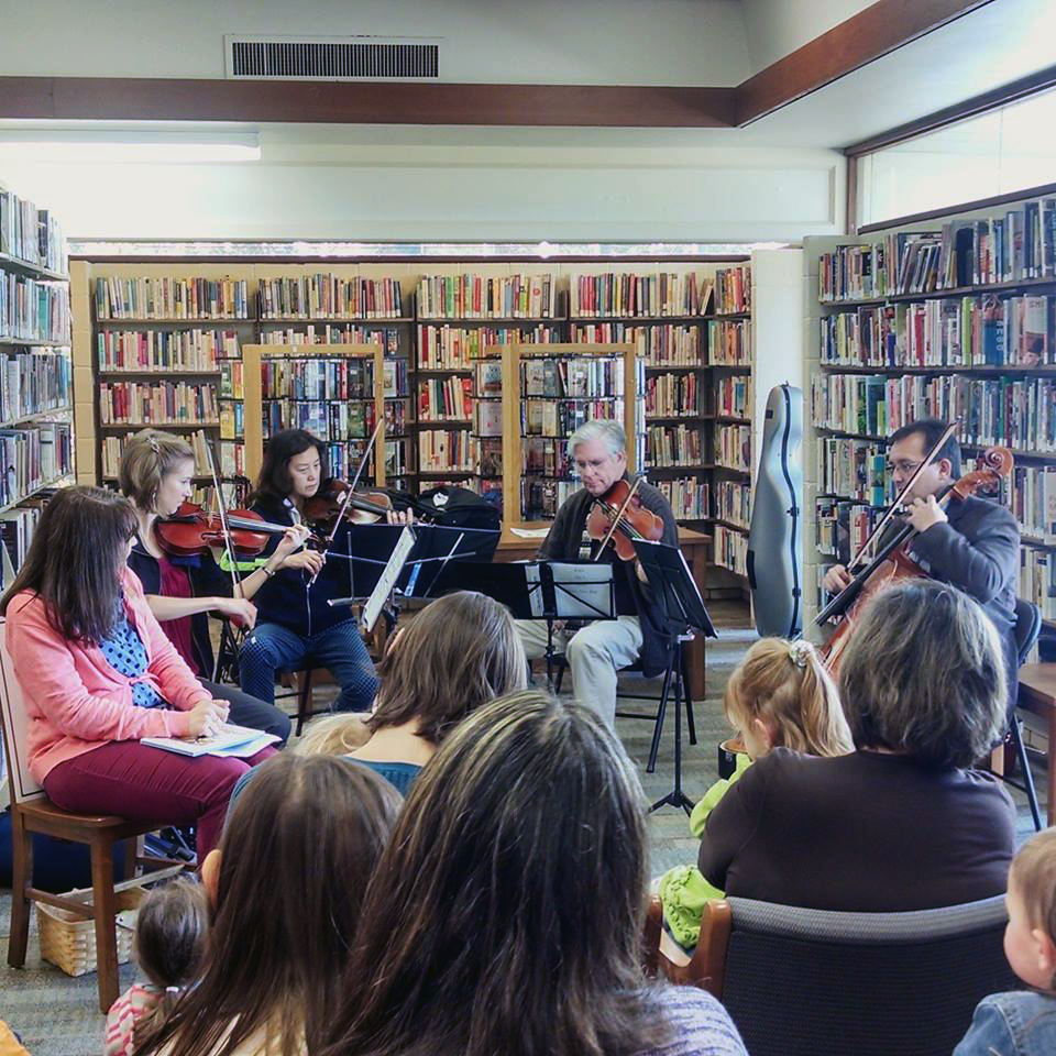musicians playing in front of library shelves