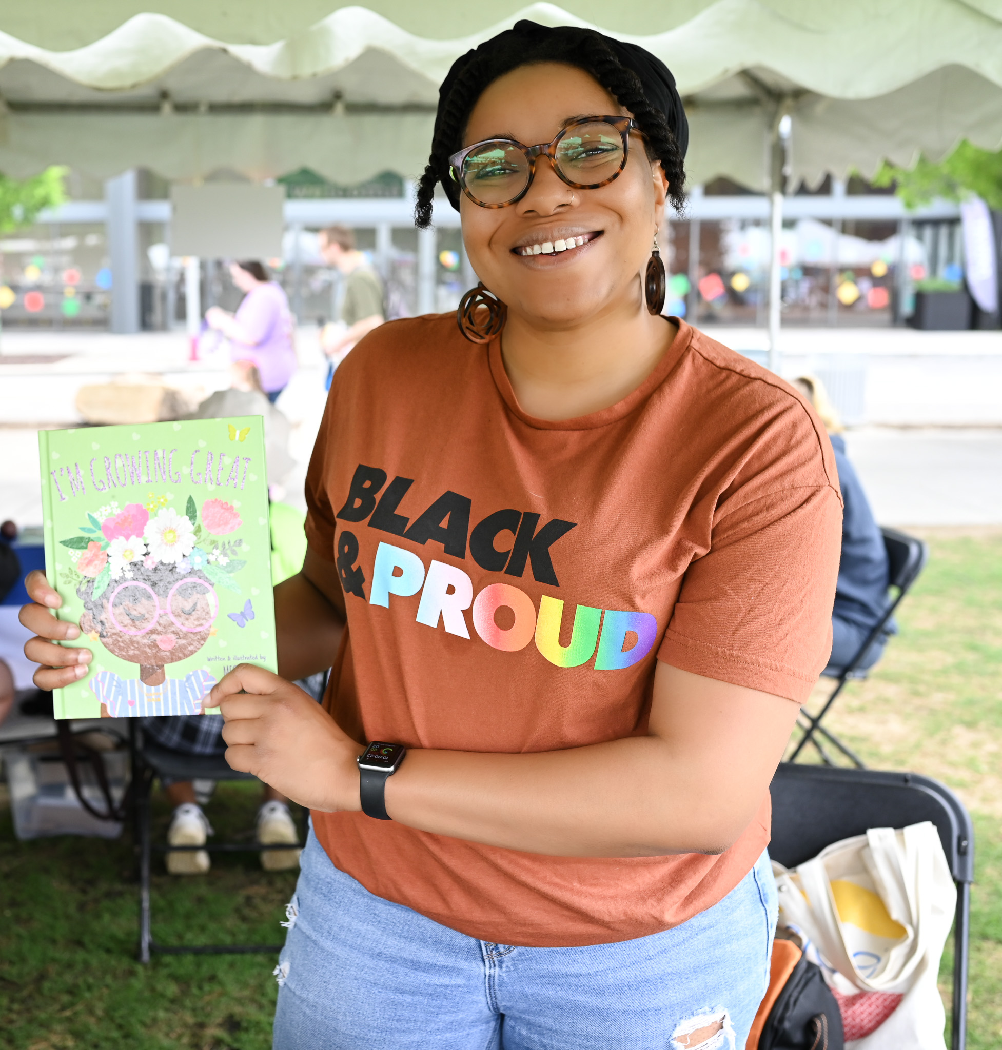 Black woman holds up the cover of children's book 'I'm Growing Great'
