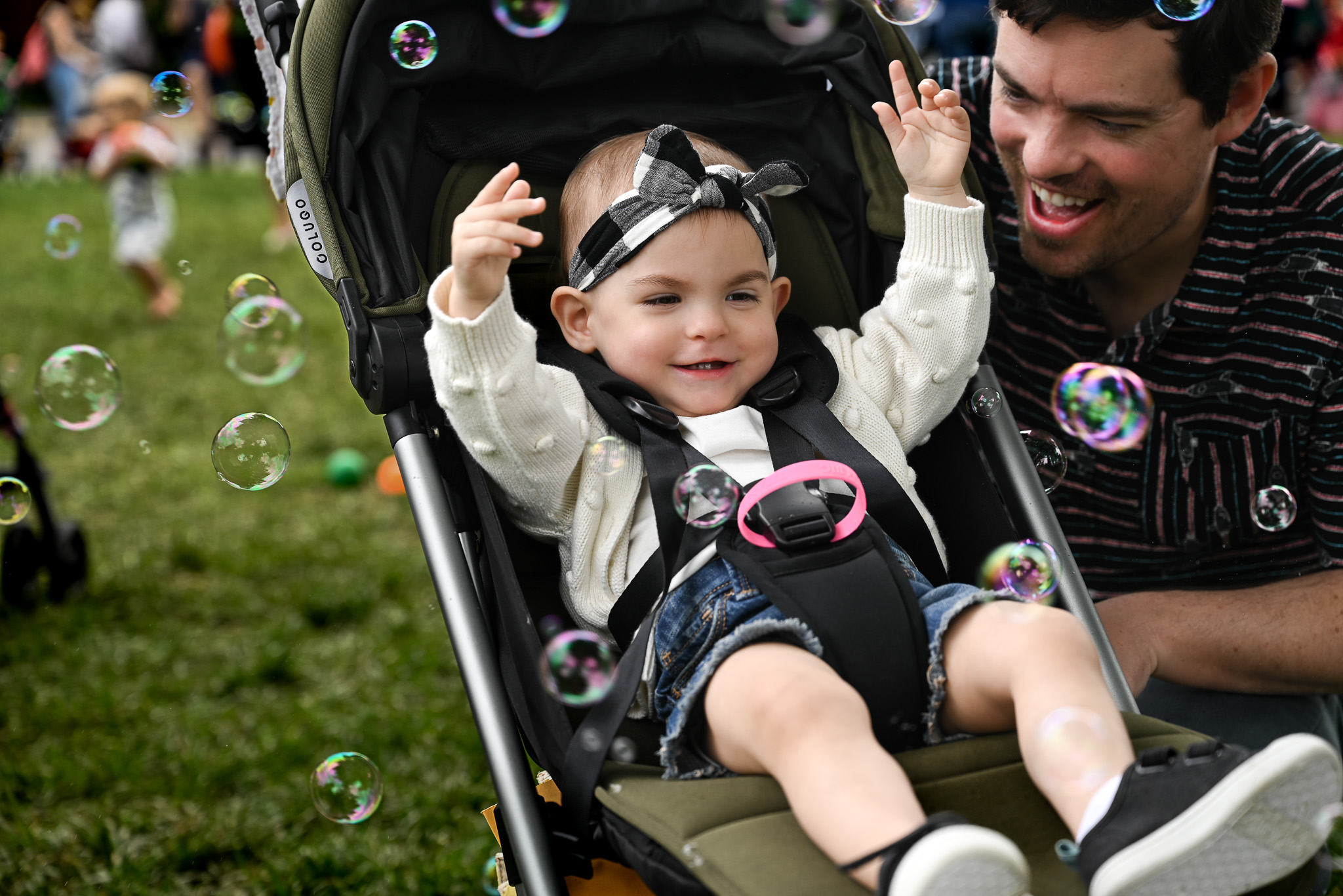 Little girl in a stroller catching bubbles