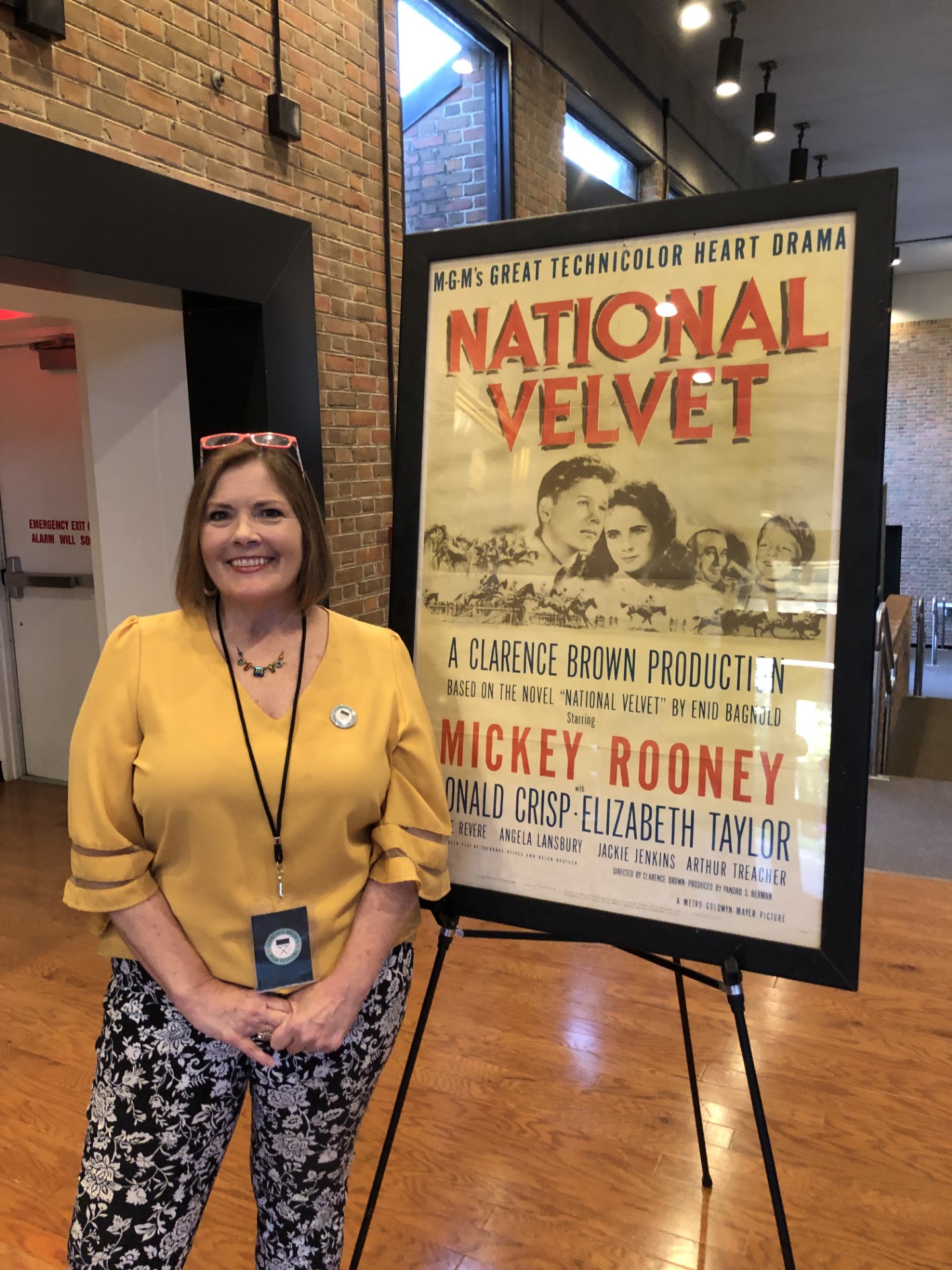 Mary Pom Claiborne stands next to vintage National Velvet film poster