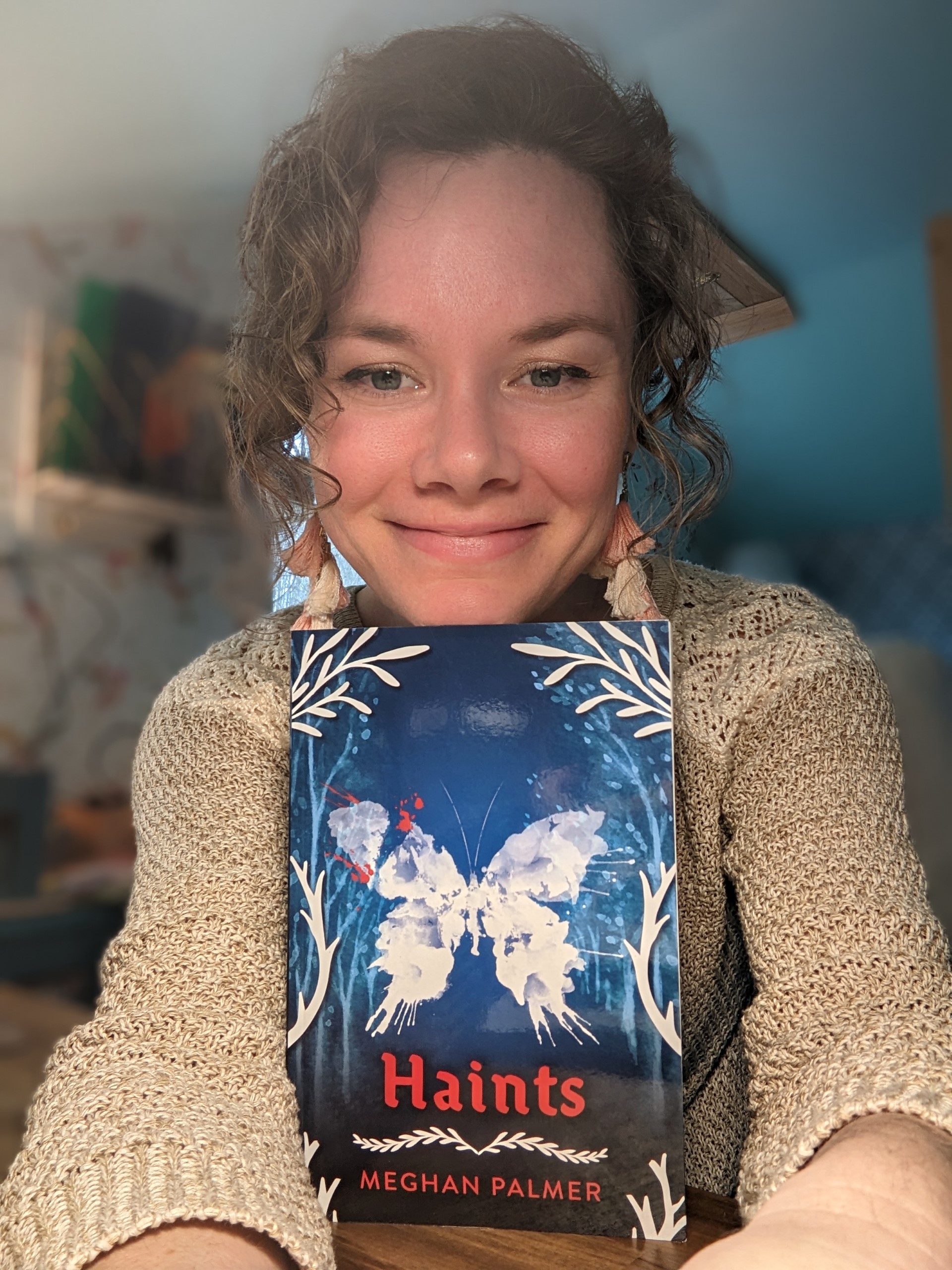 photo of author Meghan Palmer with chin resting on her book entitled haints