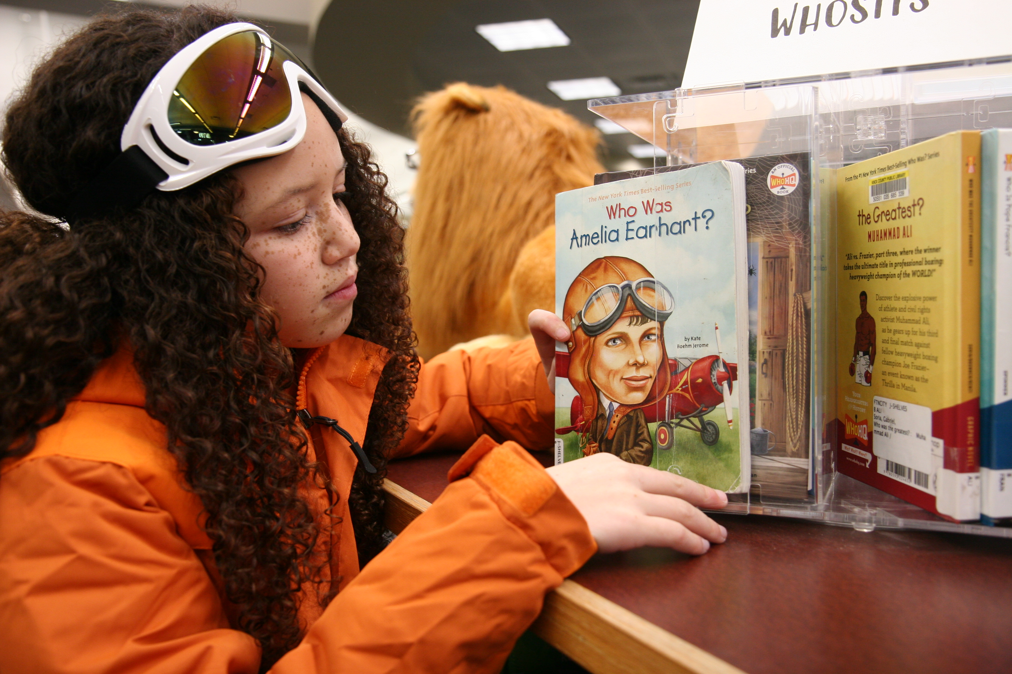 photo of young girl in snowsuit and goggles holding book of Amelia Earhart