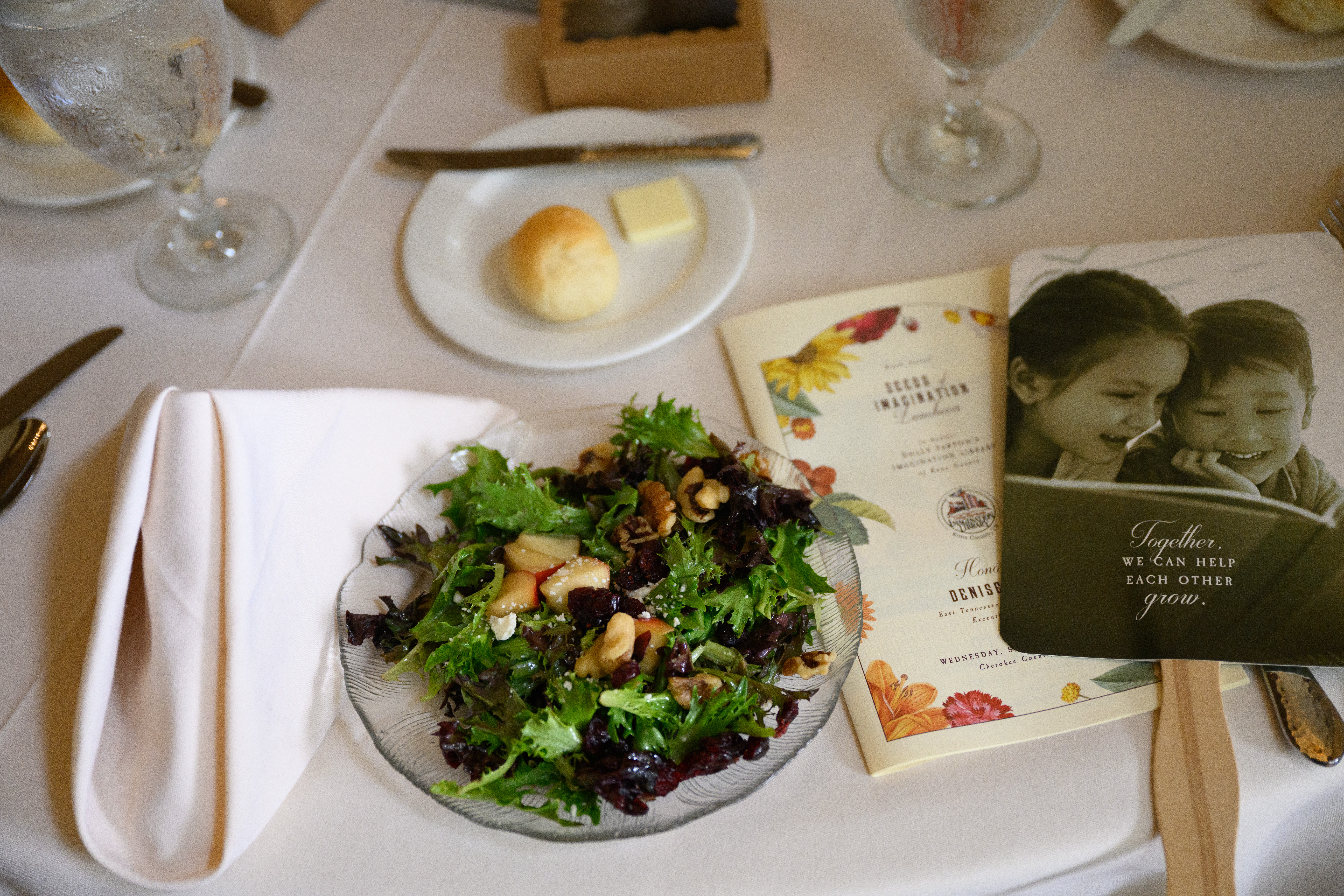 A beautiful table setting with a salad, roll, and butter