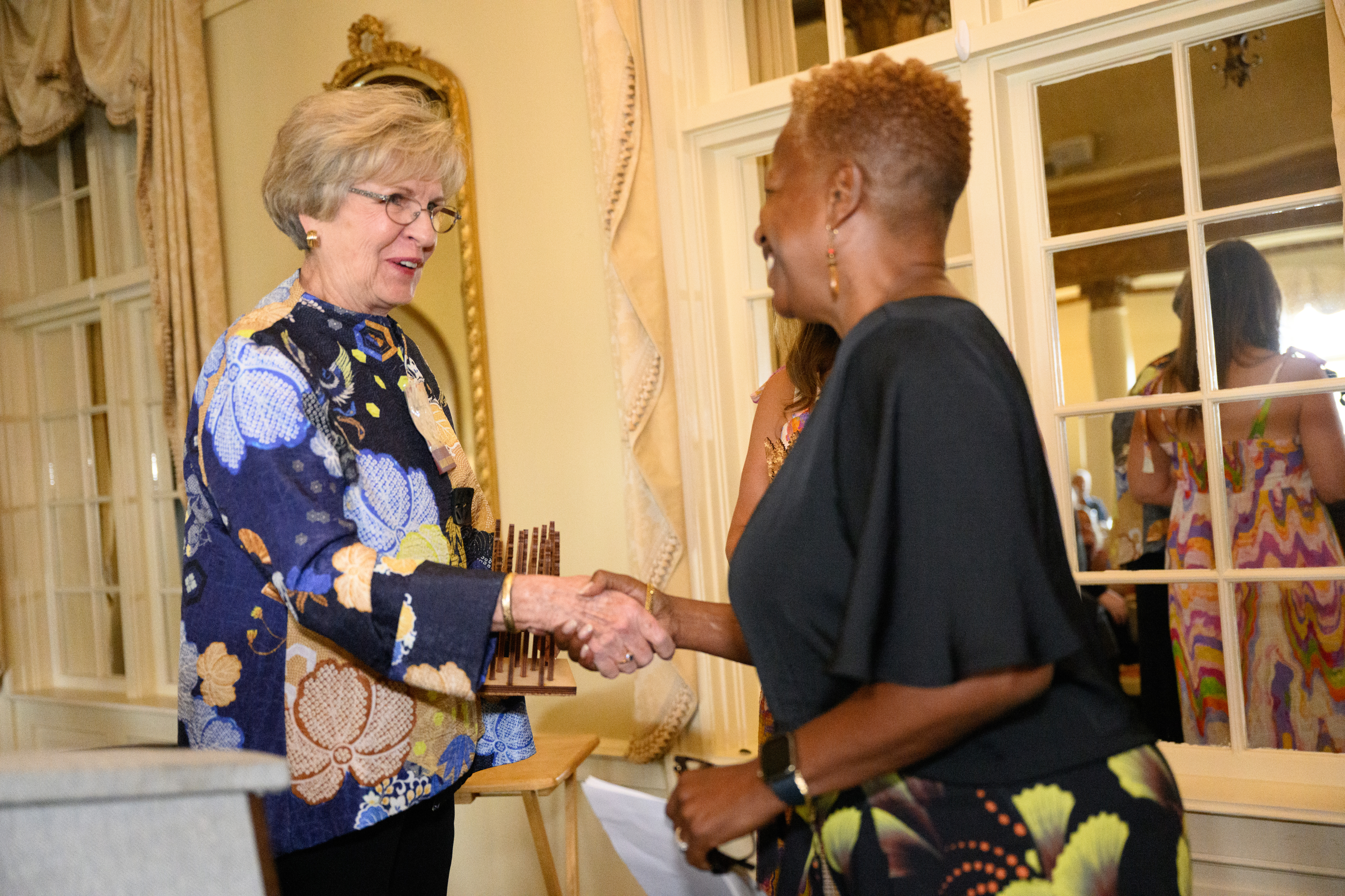 Two women shaking hands behind a gray podium