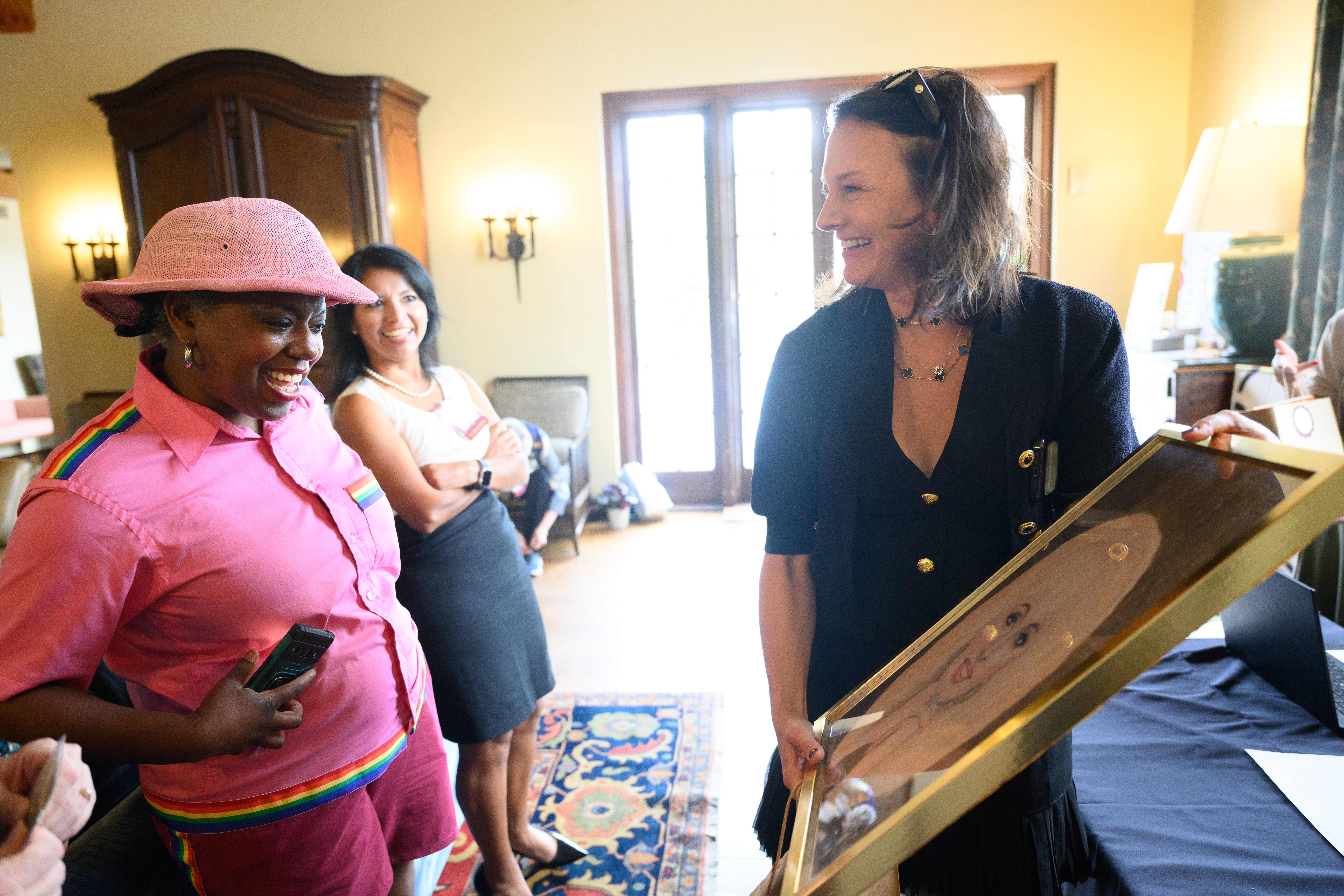 A woman smiling holding a picture as another woman admires it