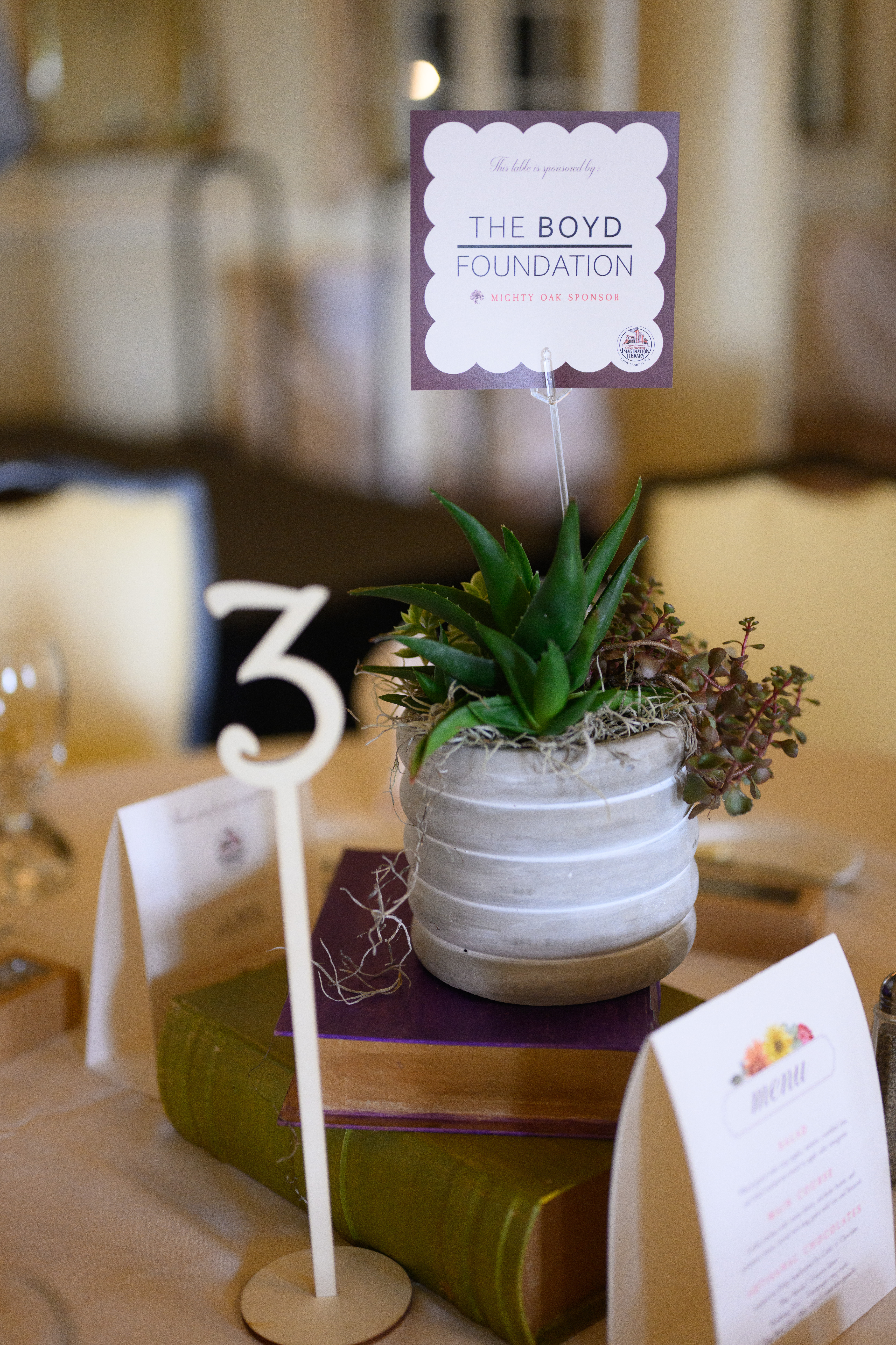 A table sign in a potted plant with a wooden table number beside it