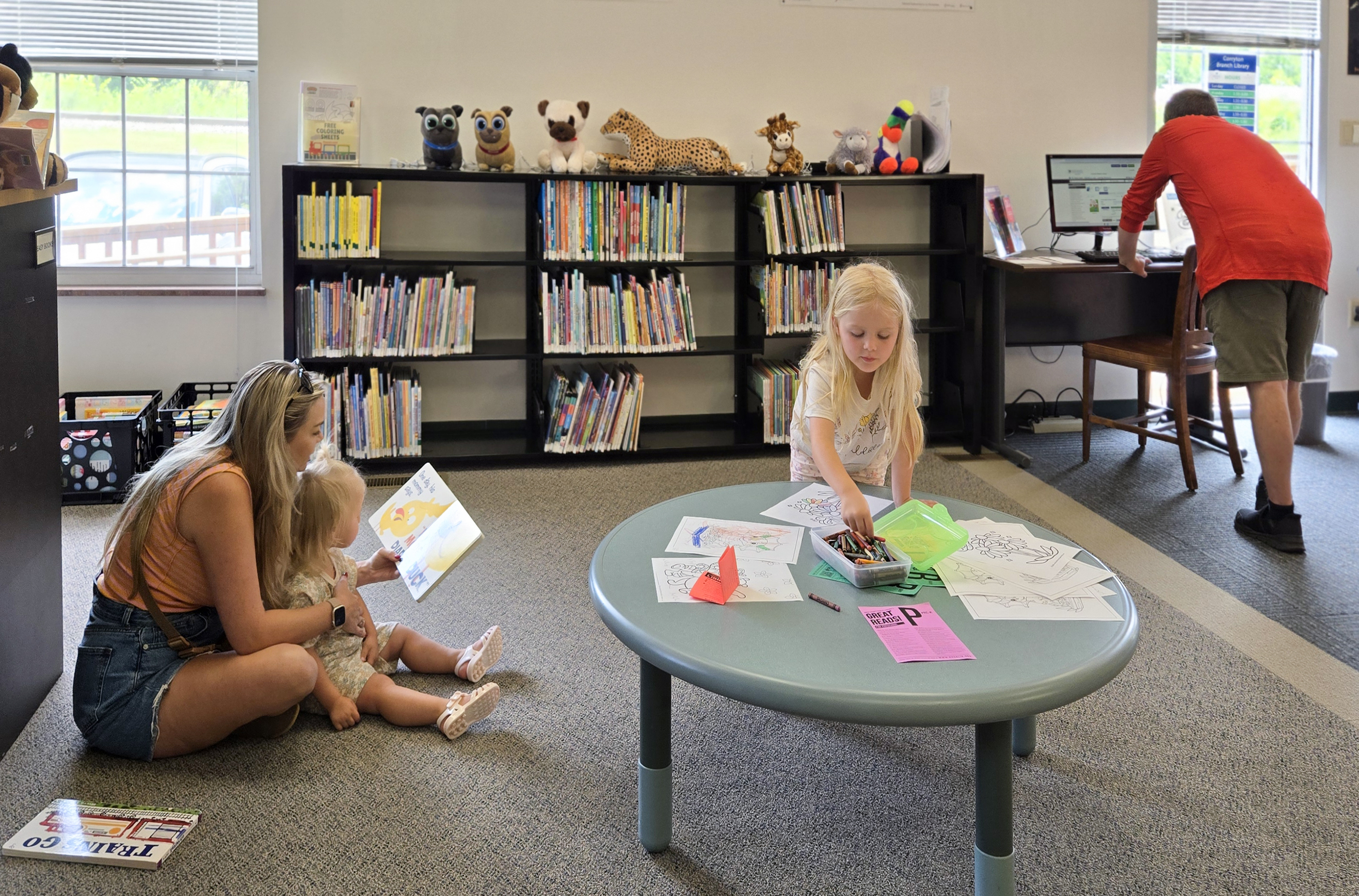 photo of mother and two children reading in a library