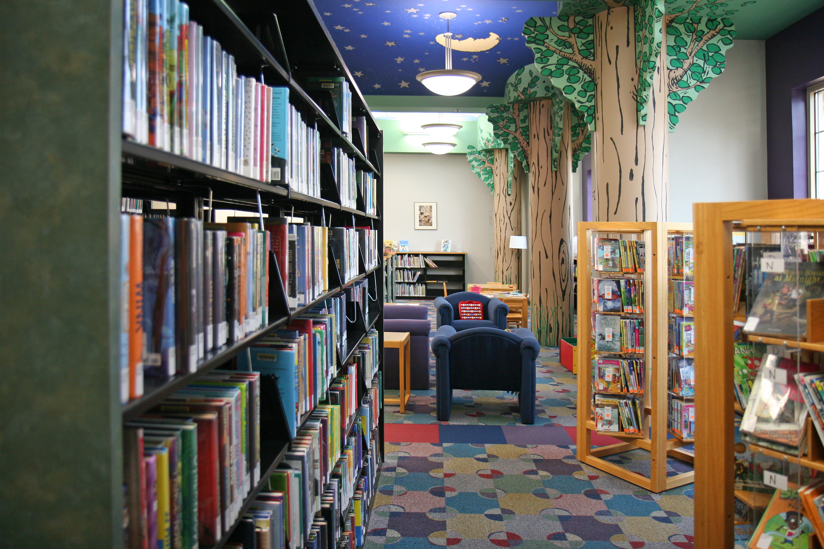 colorful children's area of a library with columns painted as trees