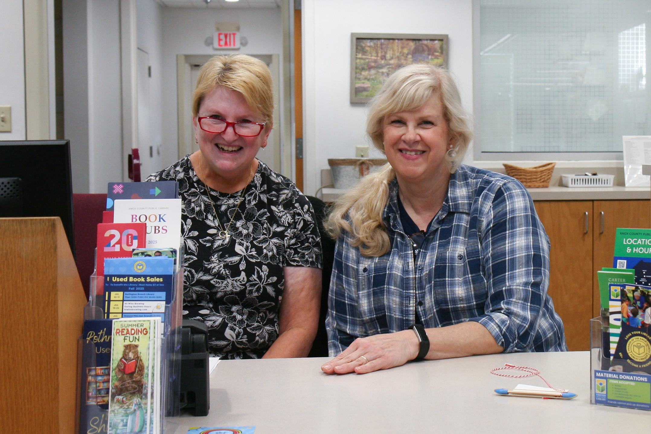 two women smiling at a library checkout counter
