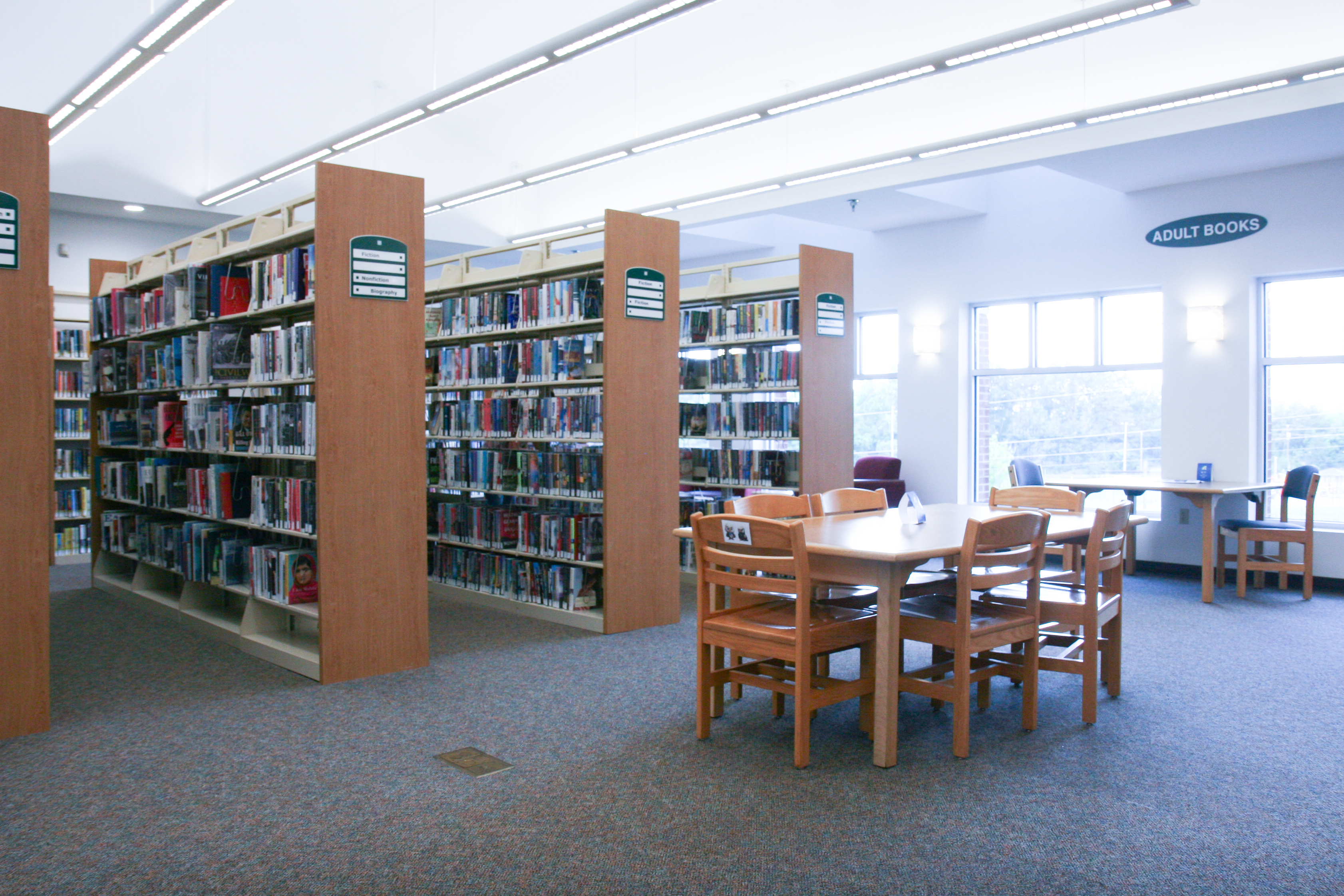 light-filled interior photo of a library with tables and book shelves