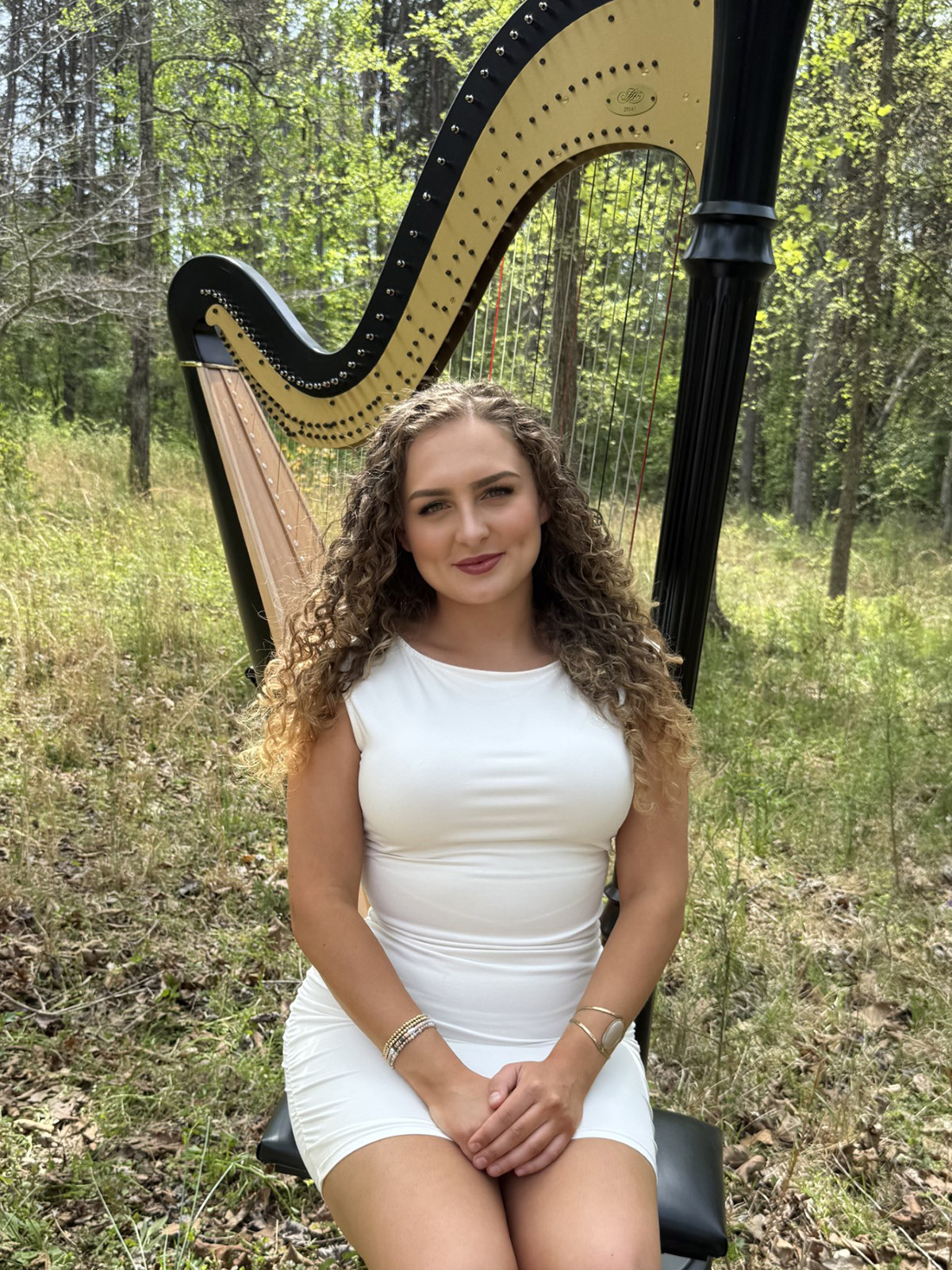 young woman seated in front of harp