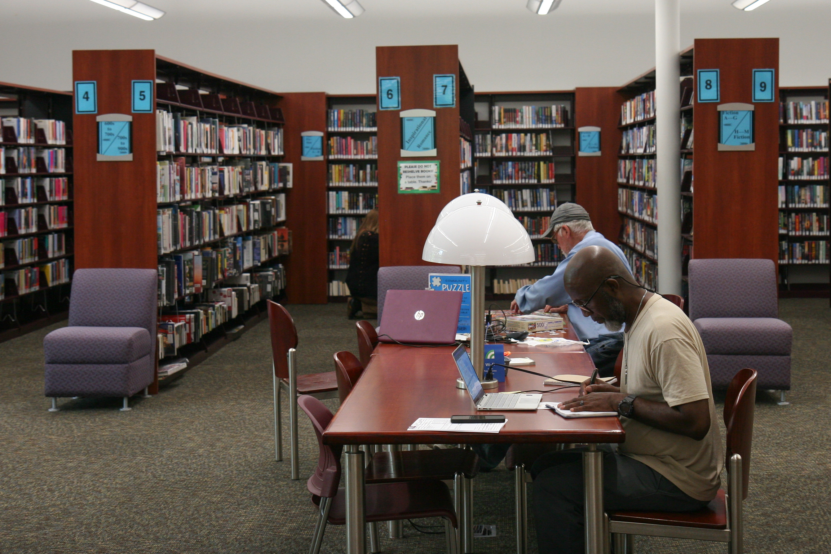 photo of a man using a laptop inside a library