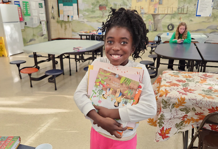 girl grinning and holding a book
