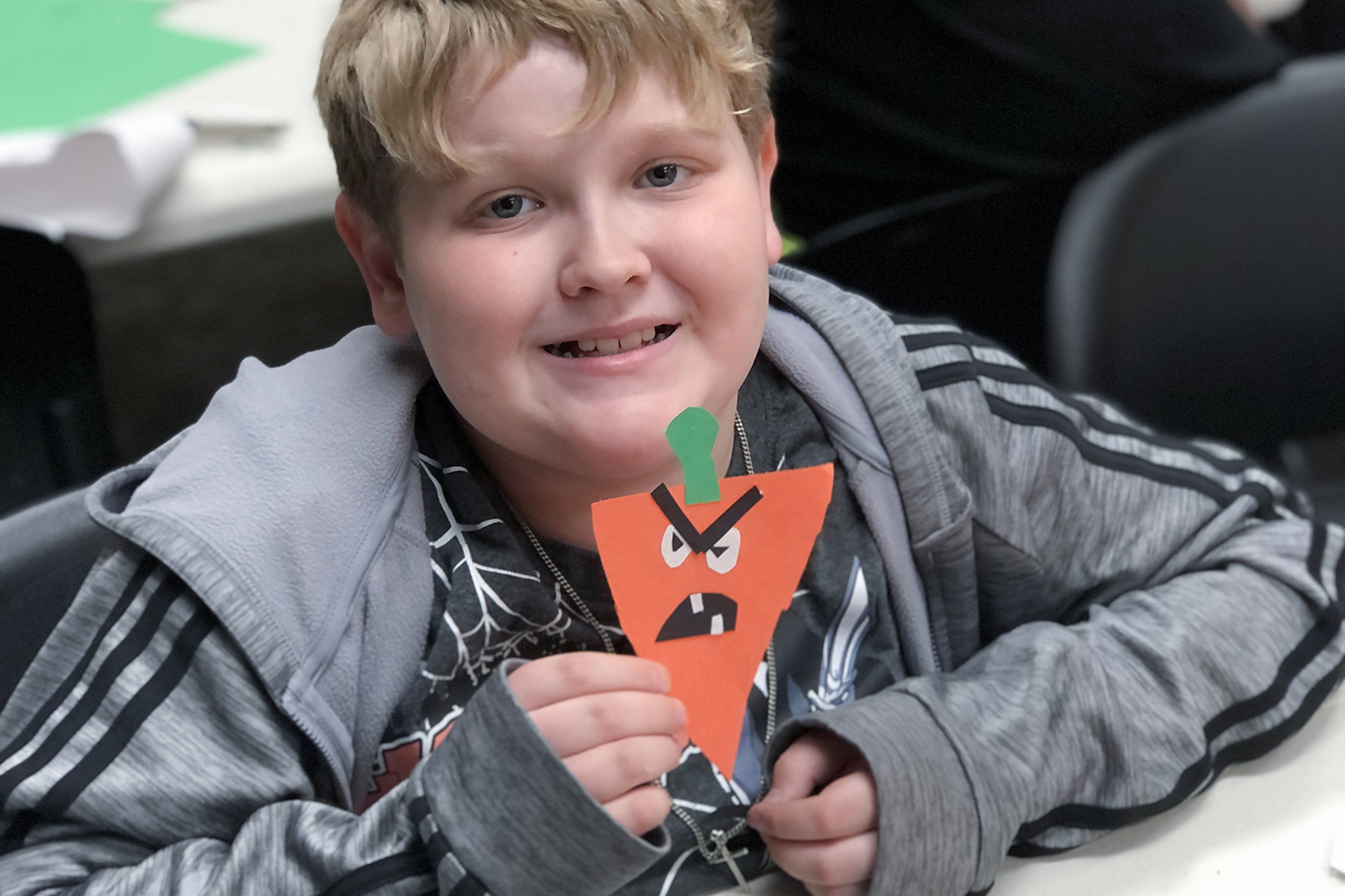 kid smiling and holding a carrot with a silly angry face