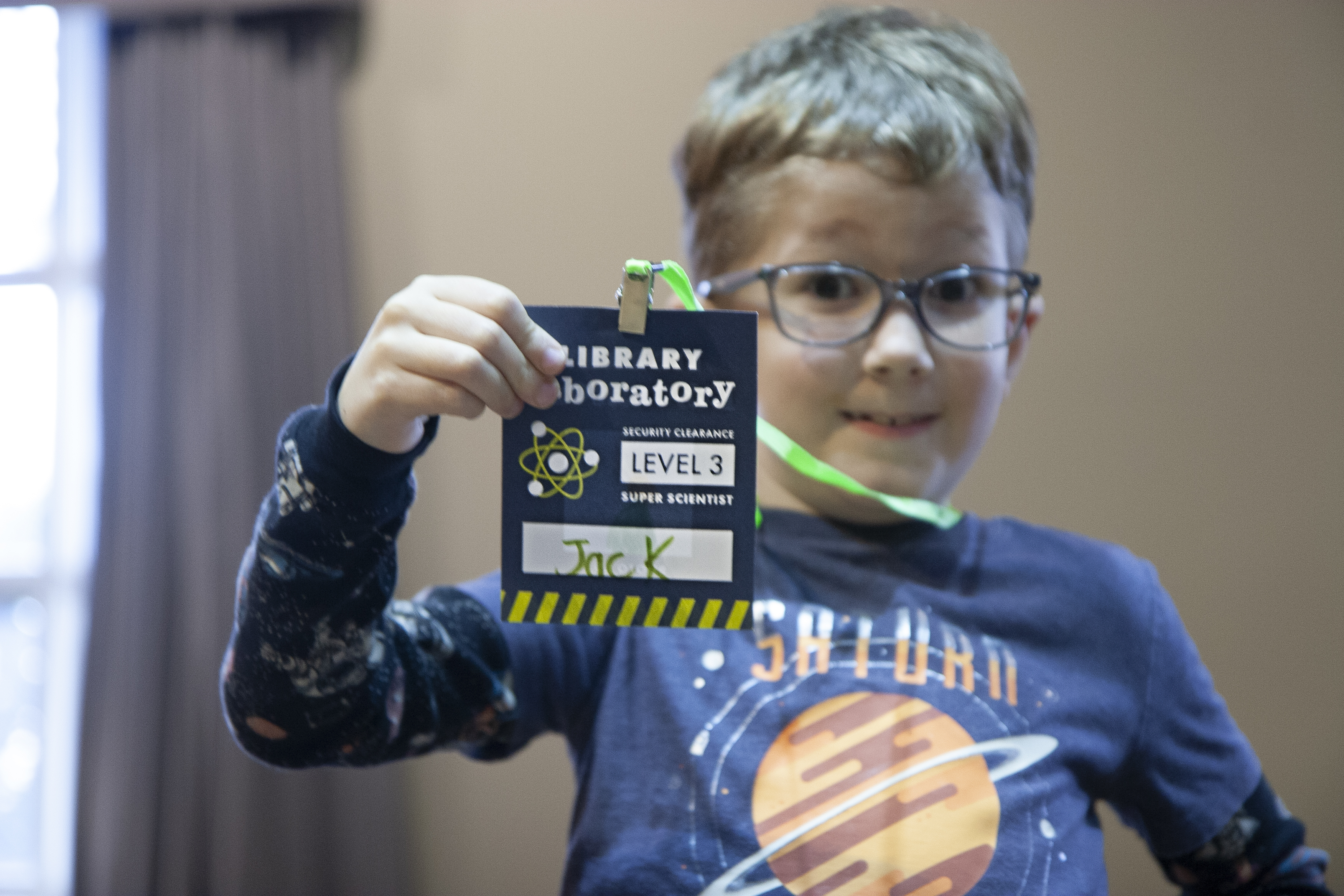 young boy proudly displaying a laboratory badge