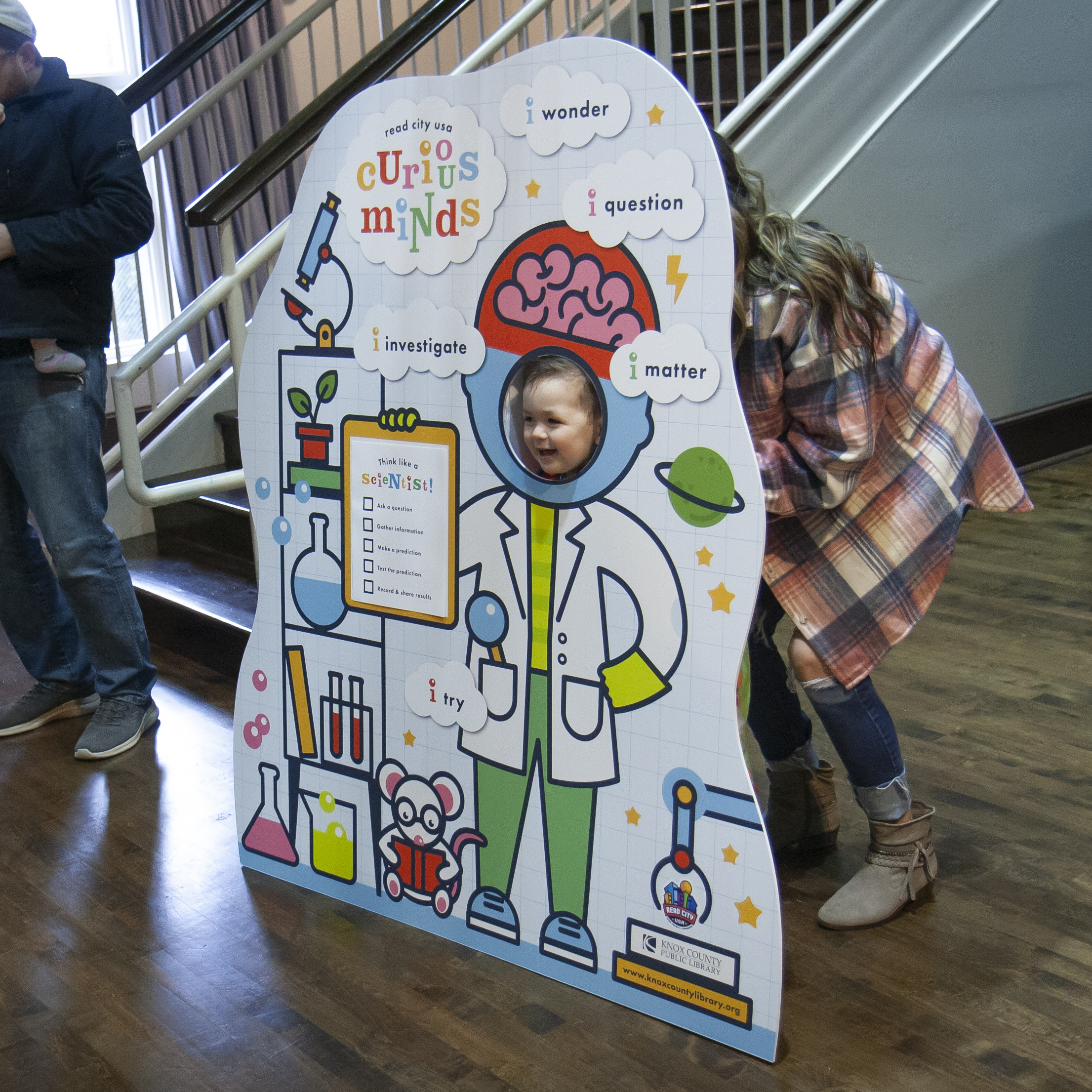 little girl smiling in a photo prop scientist cutout