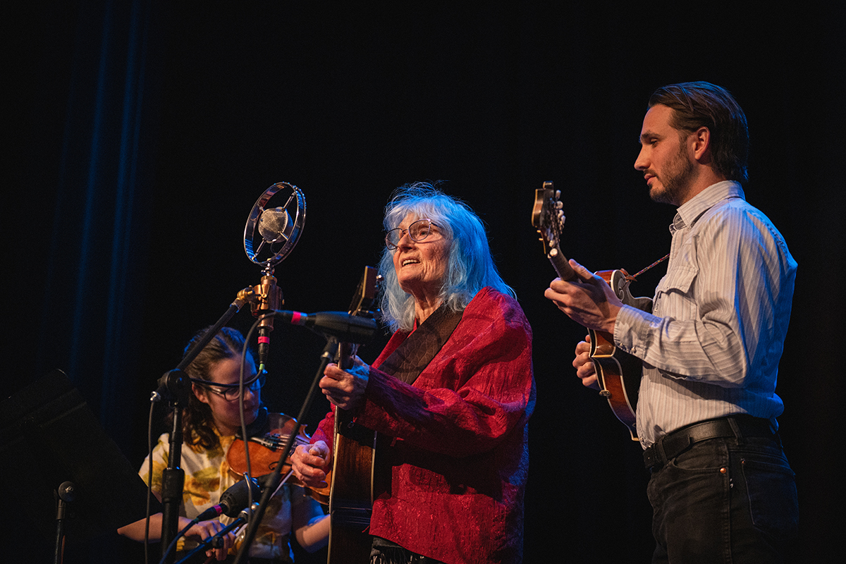 photo of Alice Gerrard and musicians on dark stage