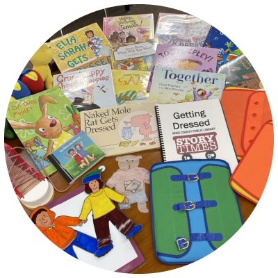 photo of books, a cd, magnetic paper doll elements, a demonstration of buckles, a demonstration of snap-fasteners, and a shoe-lacing demonstration