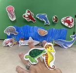 Photo of sea creatures colored and cut out, on a woman's fingers