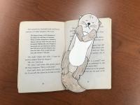 crayon-colored, paper otter on top of an open chapter book
