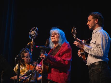 photo of Alice Gerrard and musicians on dark stage