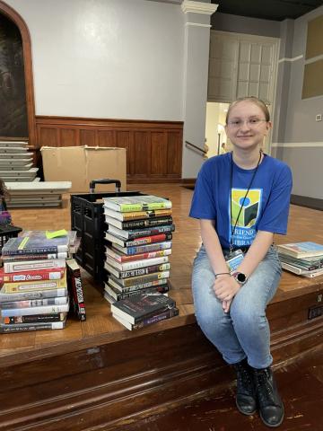 Friends Book Sale friendly face with stack of books