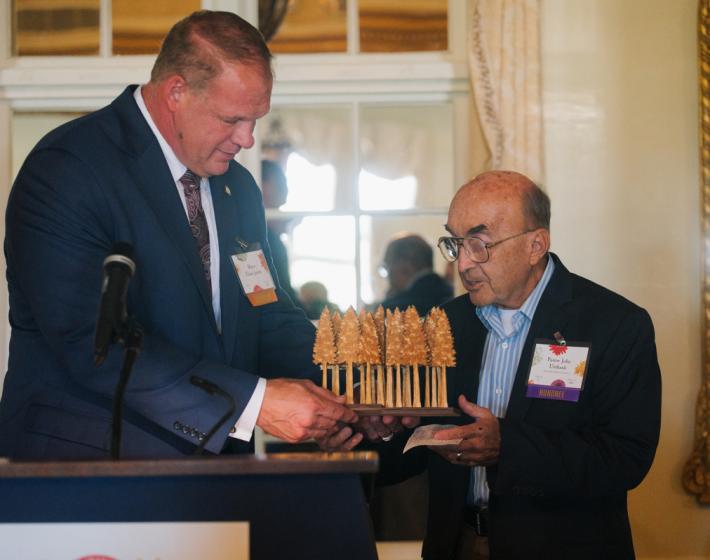 photo of Mayor Glenn Jacobs handing Pastor John a wooden forest of trees award