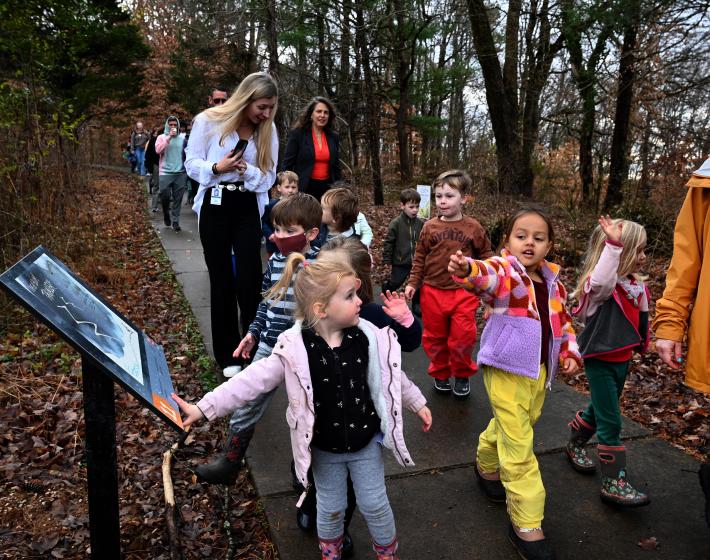 preschool children walk along a trail with story panels