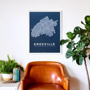 Brown leather chair with blue Knoxville Neighborhood Map in a white frame displayed above