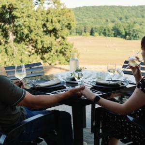 photo of a couple at a bistro table on a balcony overlooking a field